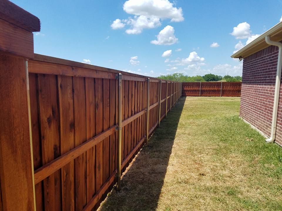 A wooden fence is in the backyard of a house.