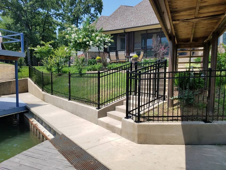 A metal fence surrounds a dock and stairs leading to a house.