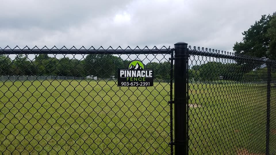 A chain link fence with a pinnacle tree sign on it