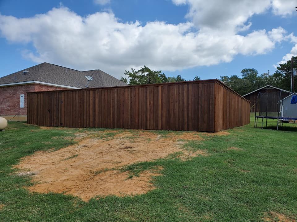 A wooden fence is in the middle of a lush green field.