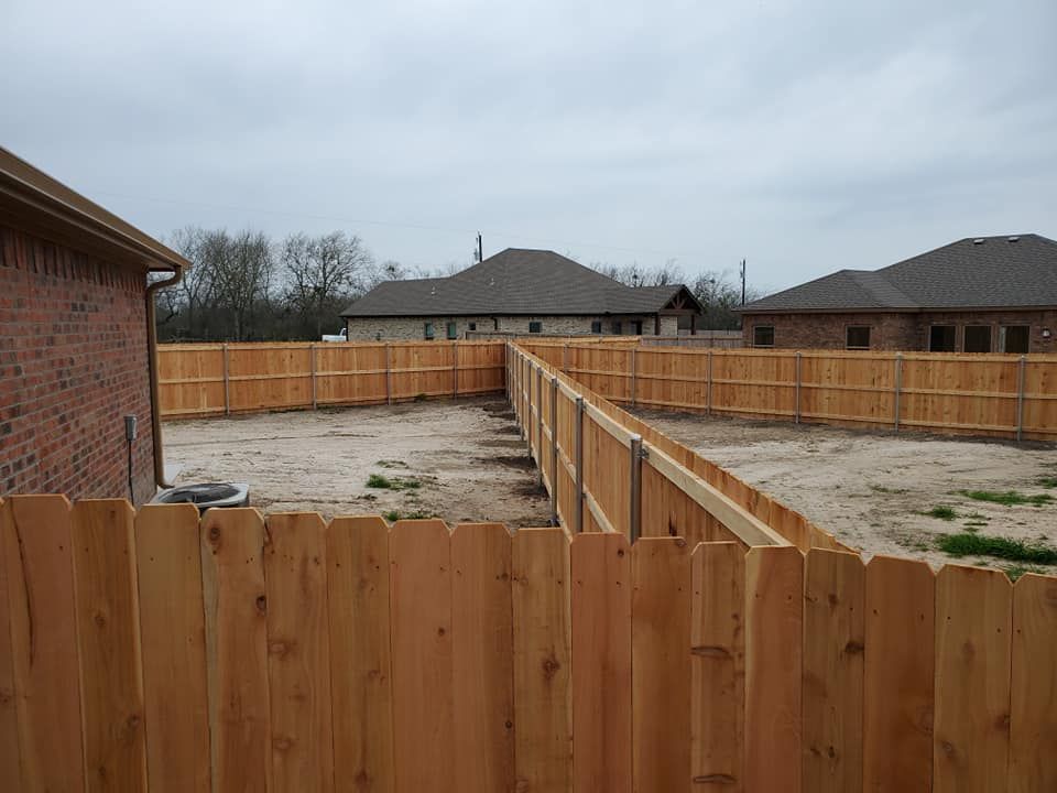 A wooden fence surrounds a brick house in a residential area