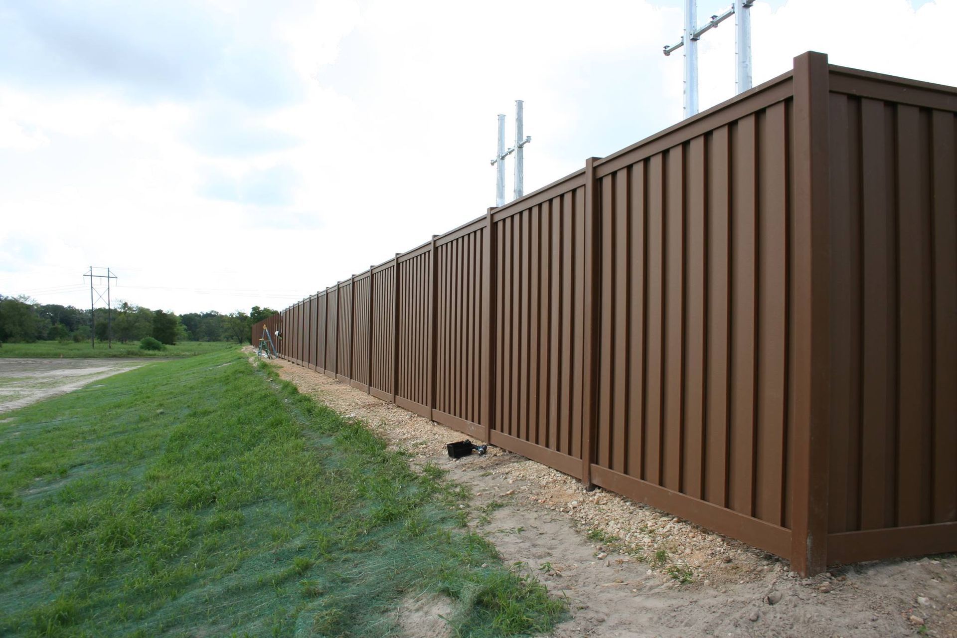 A long brown wooden fence surrounds a grassy field.