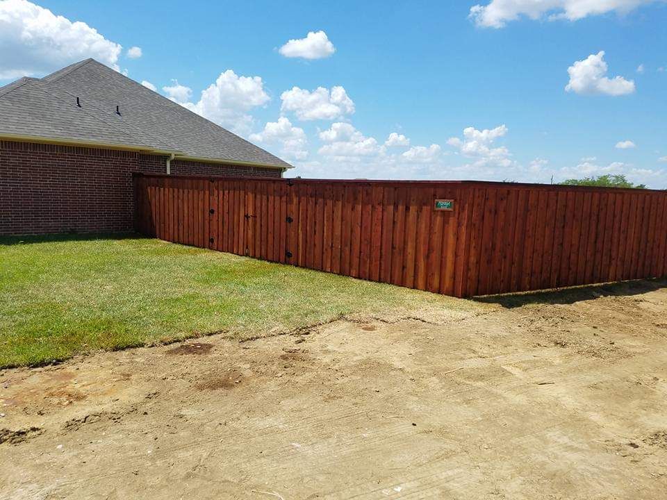 A wooden fence is in the backyard of a house.