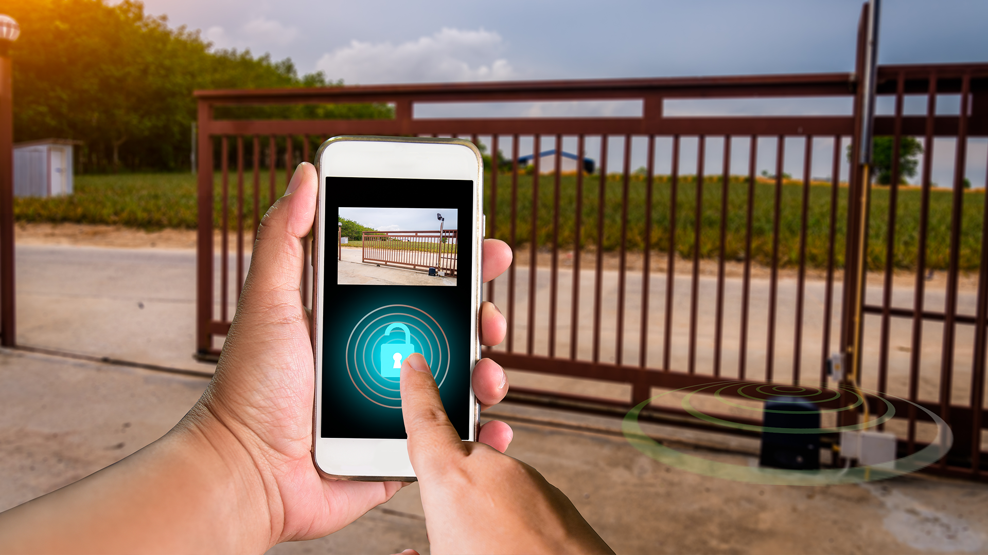 A person is holding a cell phone in front of a sliding gate.