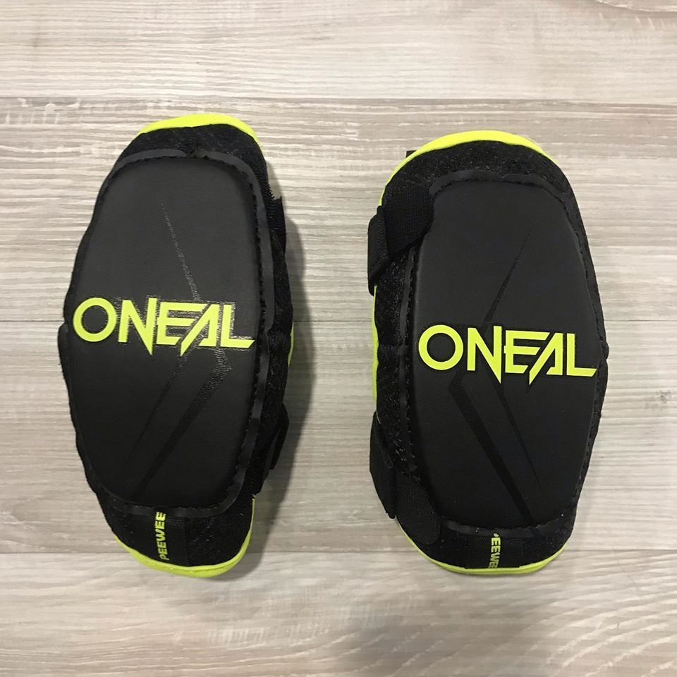 Par de coderas O'Neal negras y amarillas sobre una superficie de madera.