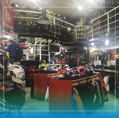 Interior de una tienda de artículos para motocicletas con cascos, ropa y exhibiciones de mercadería.