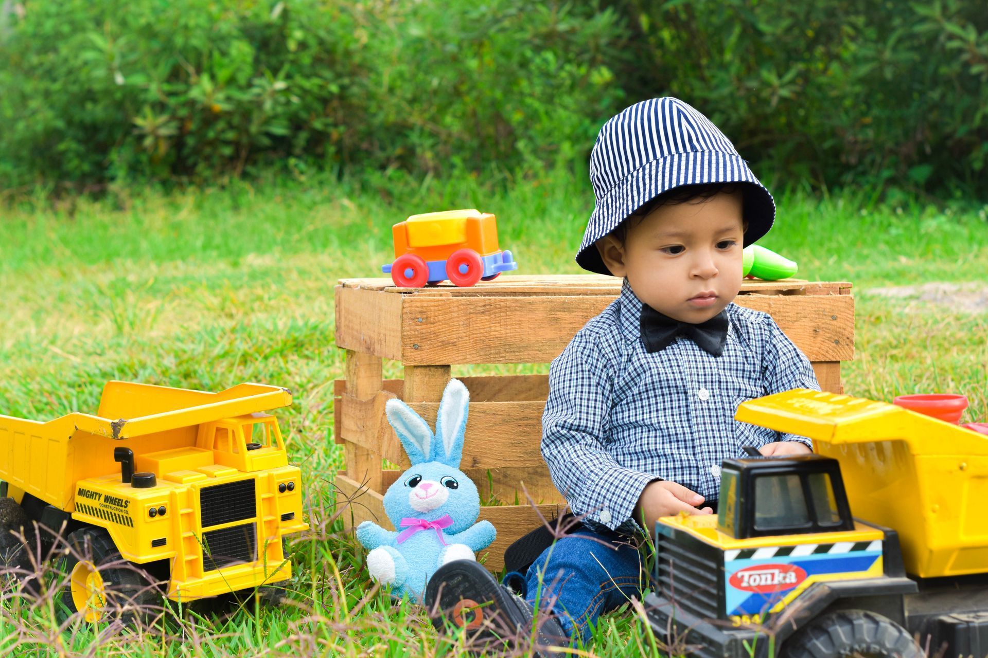 Un niño pequeño está jugando con camiones de juguete en el césped.