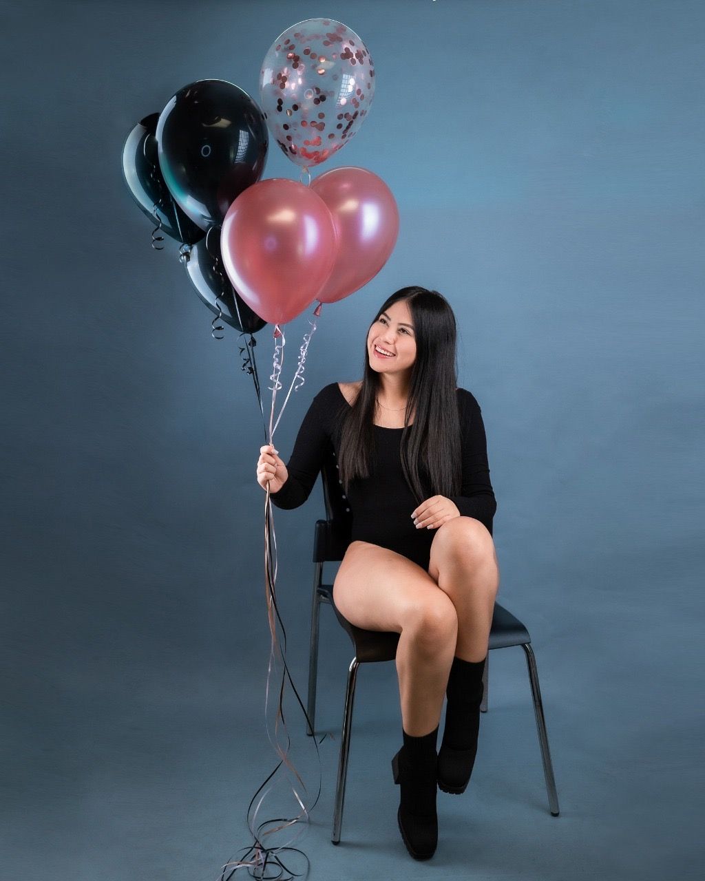 Una mujer está sentada en una silla sosteniendo globos.