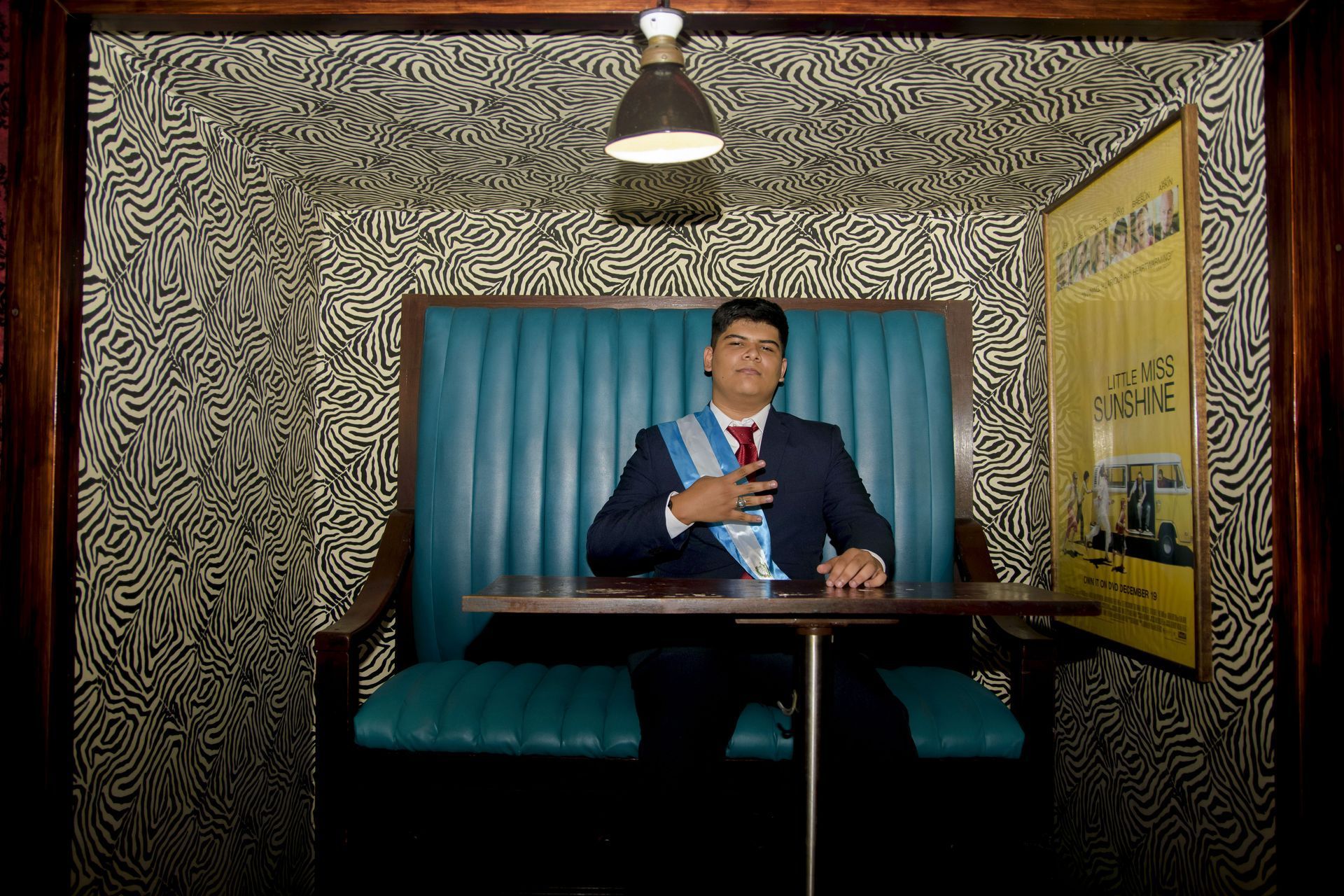 Un hombre con traje y corbata está sentado en una mesa en una cabina.