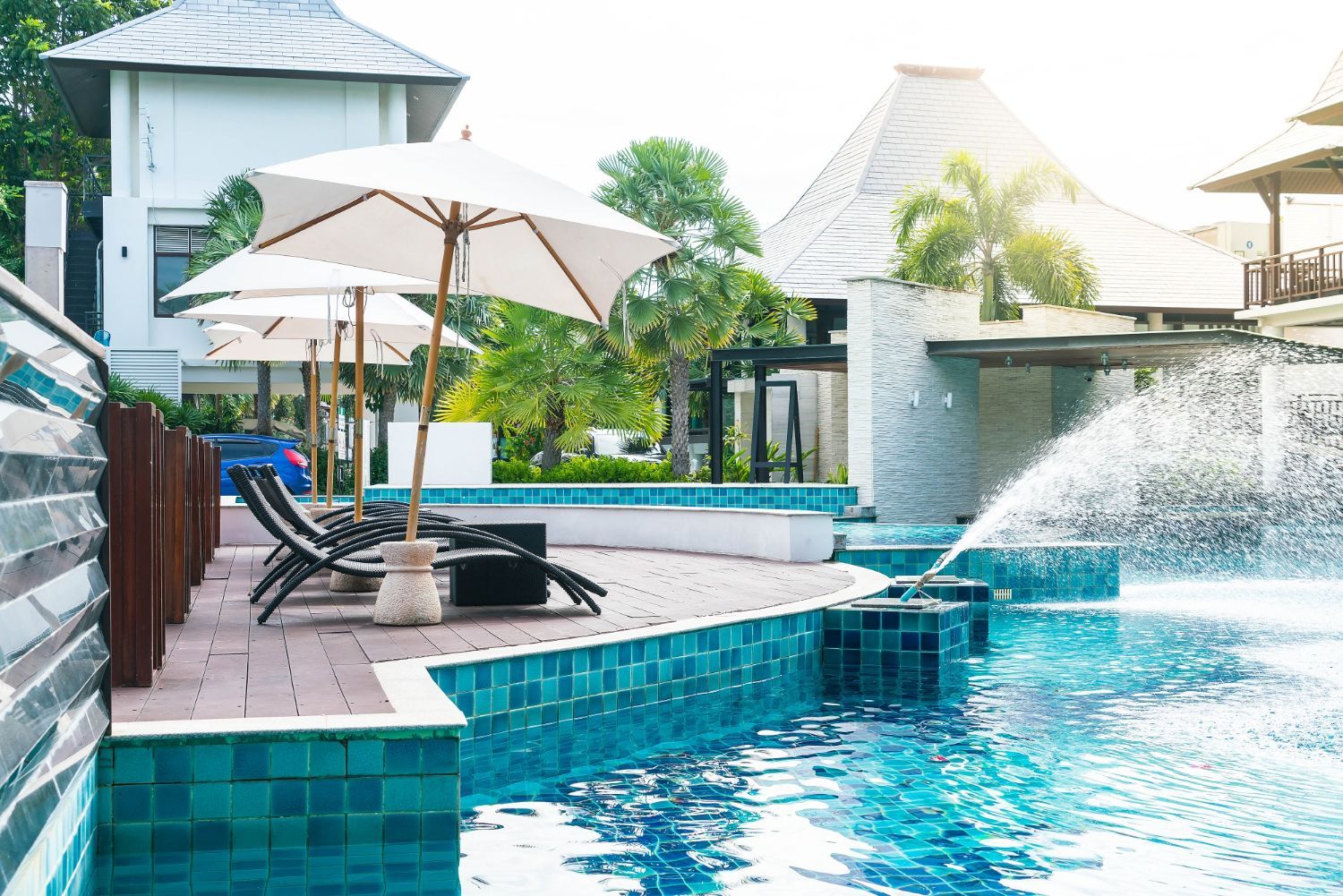 There is a swimming pool with umbrellas and chairs around it.