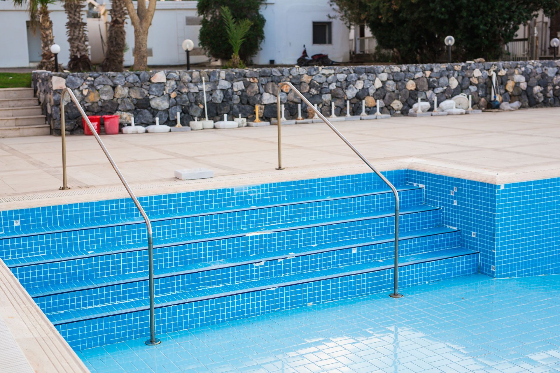 A swimming pool with blue tiles and stairs leading to it