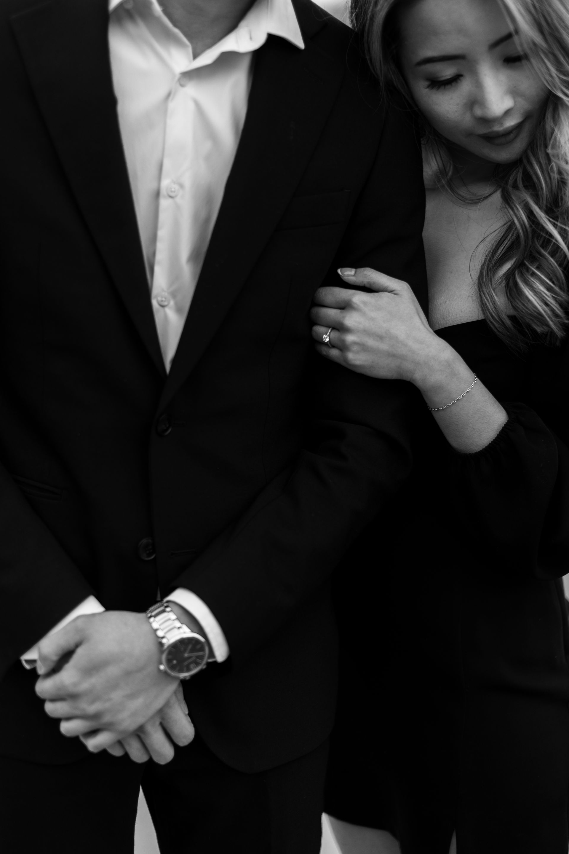 A man in a suit and a woman in a black dress are standing next to each other in a black and white photo.