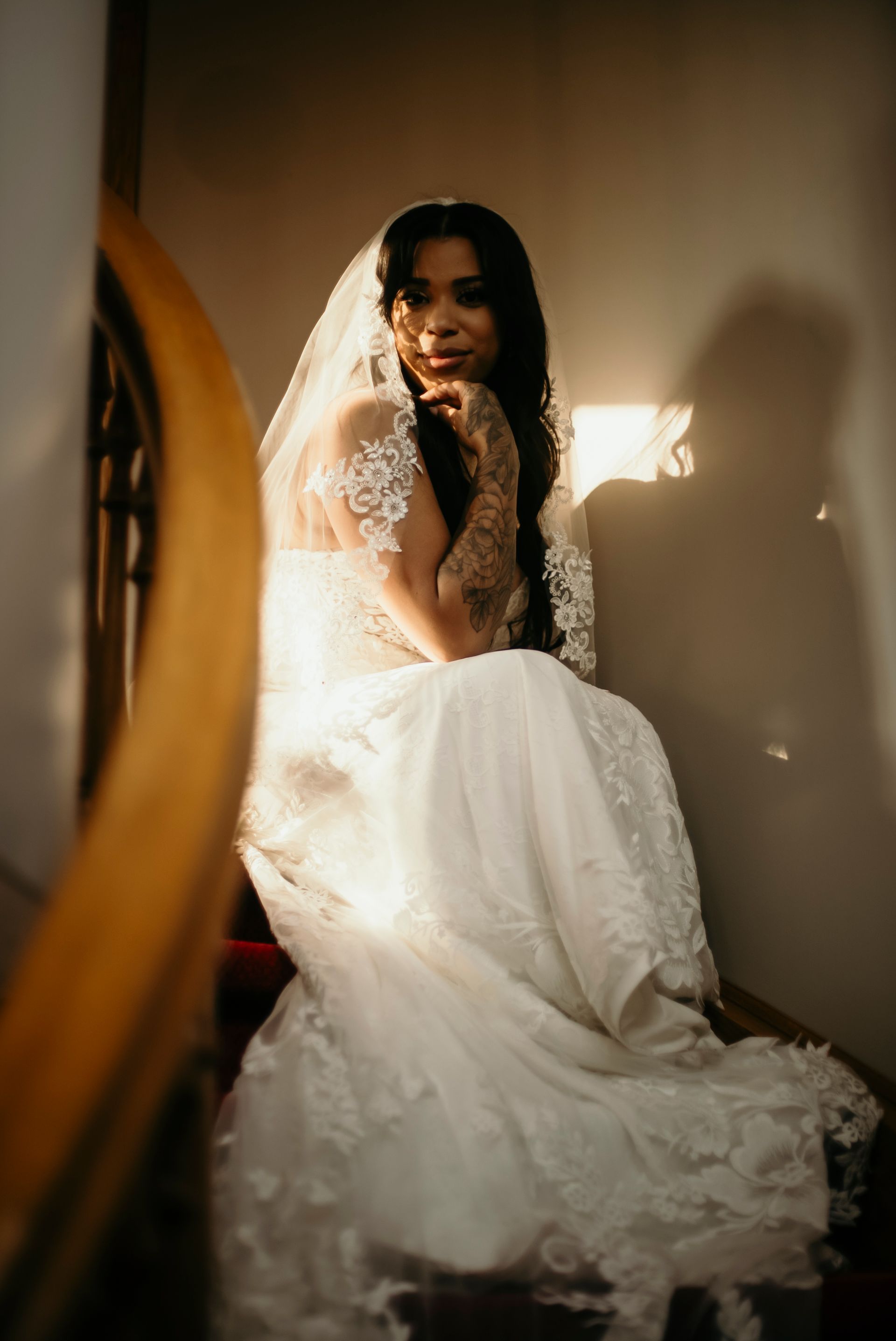 A woman in a wedding dress and veil is sitting on a set of stairs.