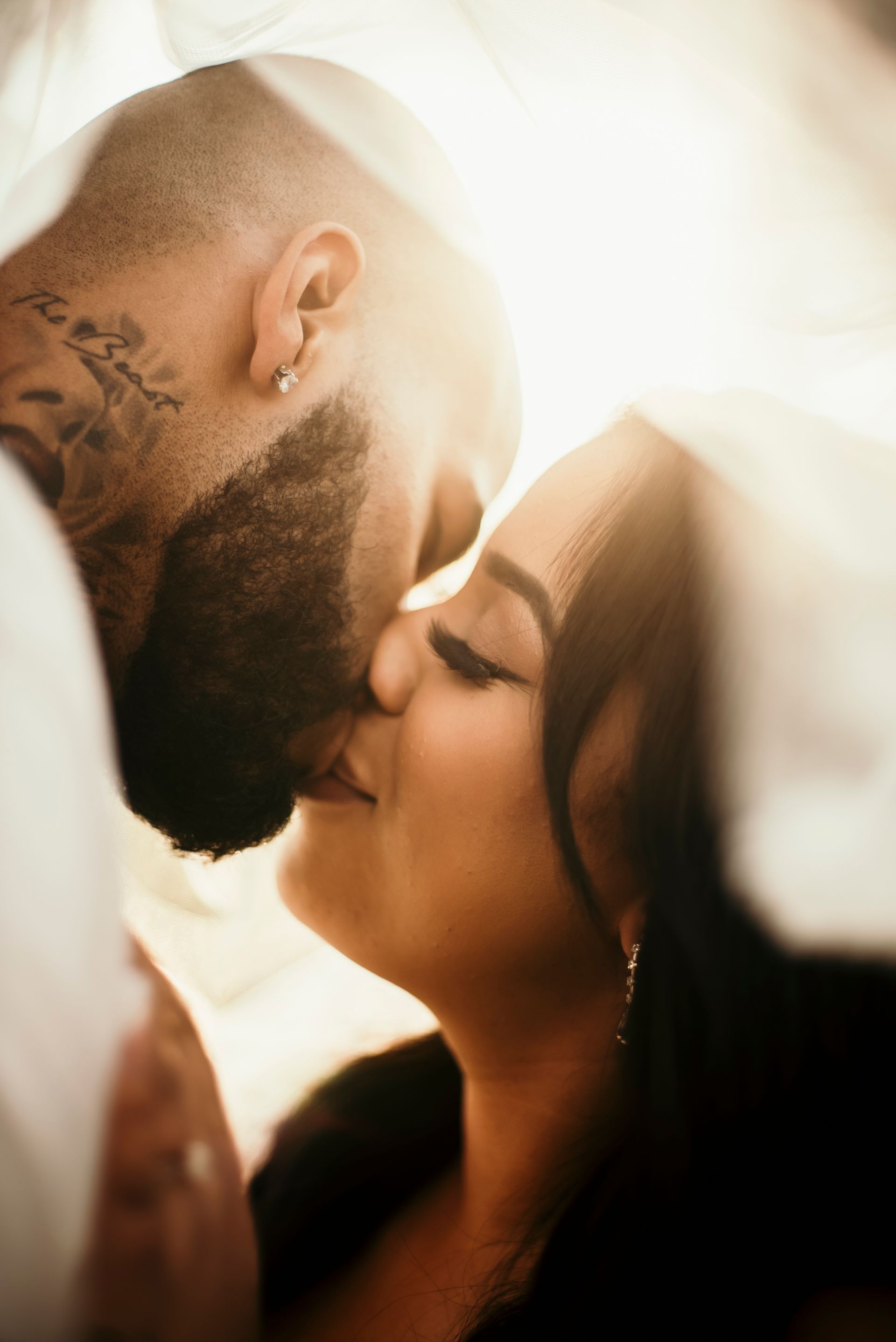 A man and a woman are kissing under a veil.