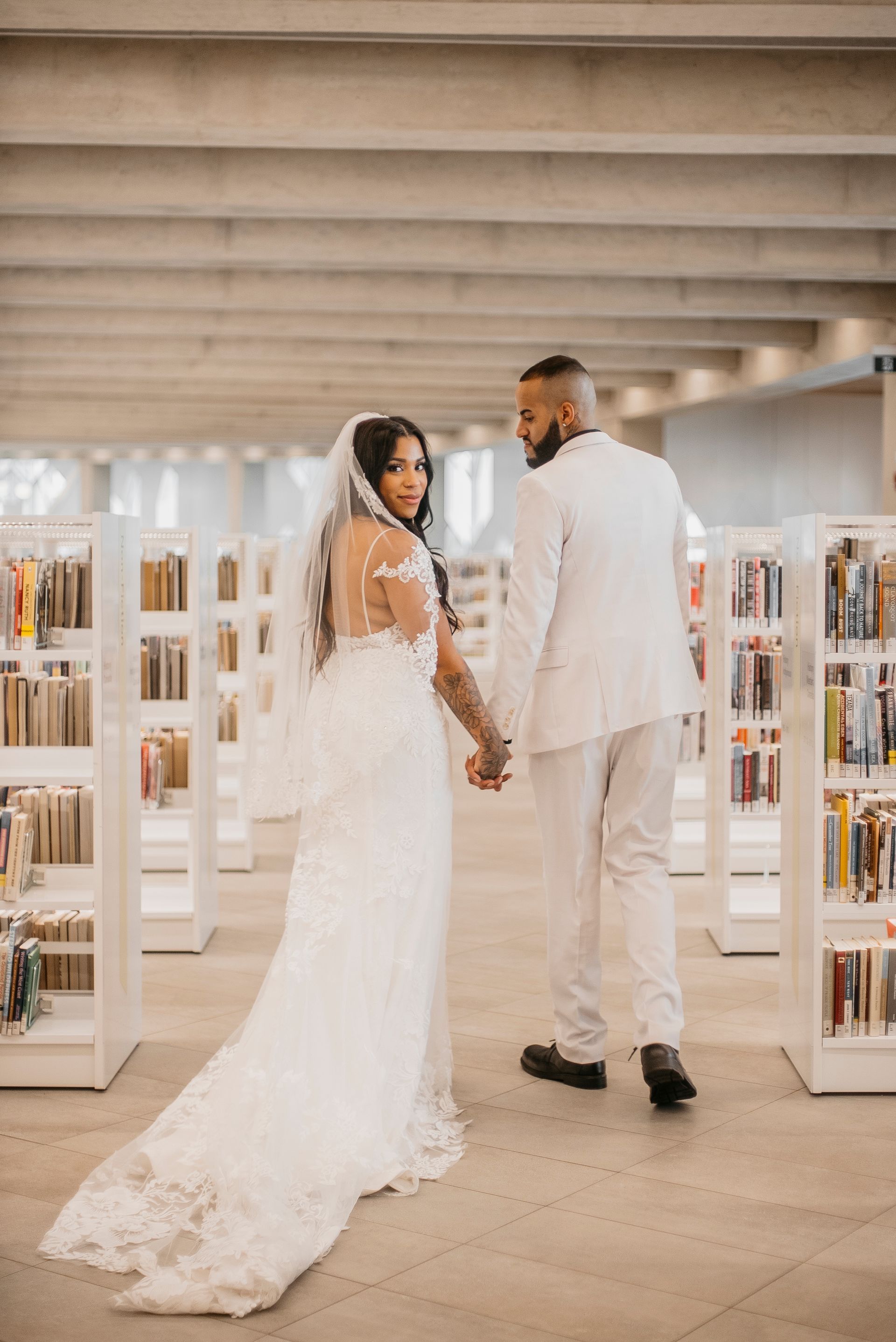 A bride and groom are holding hands in a library.