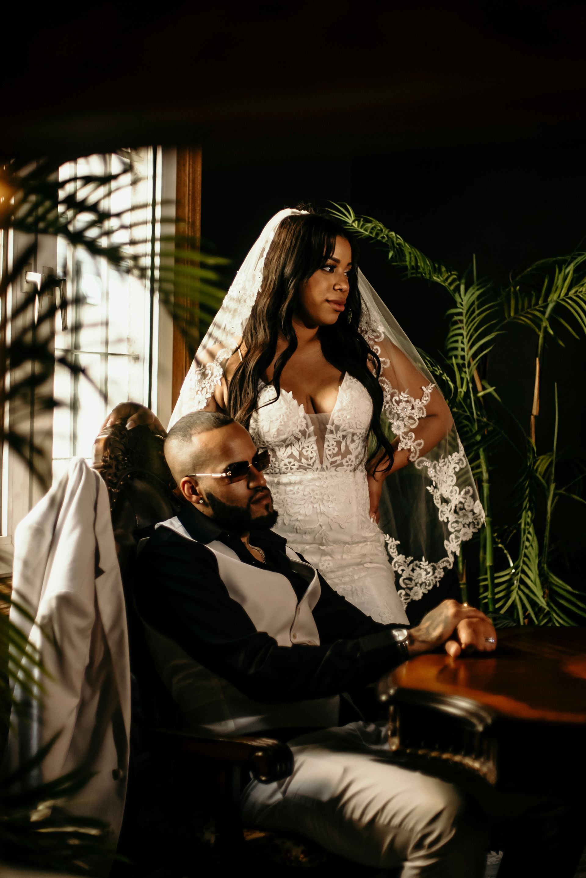 A bride and groom are posing for a picture while the bride is sitting on the groom 's lap.