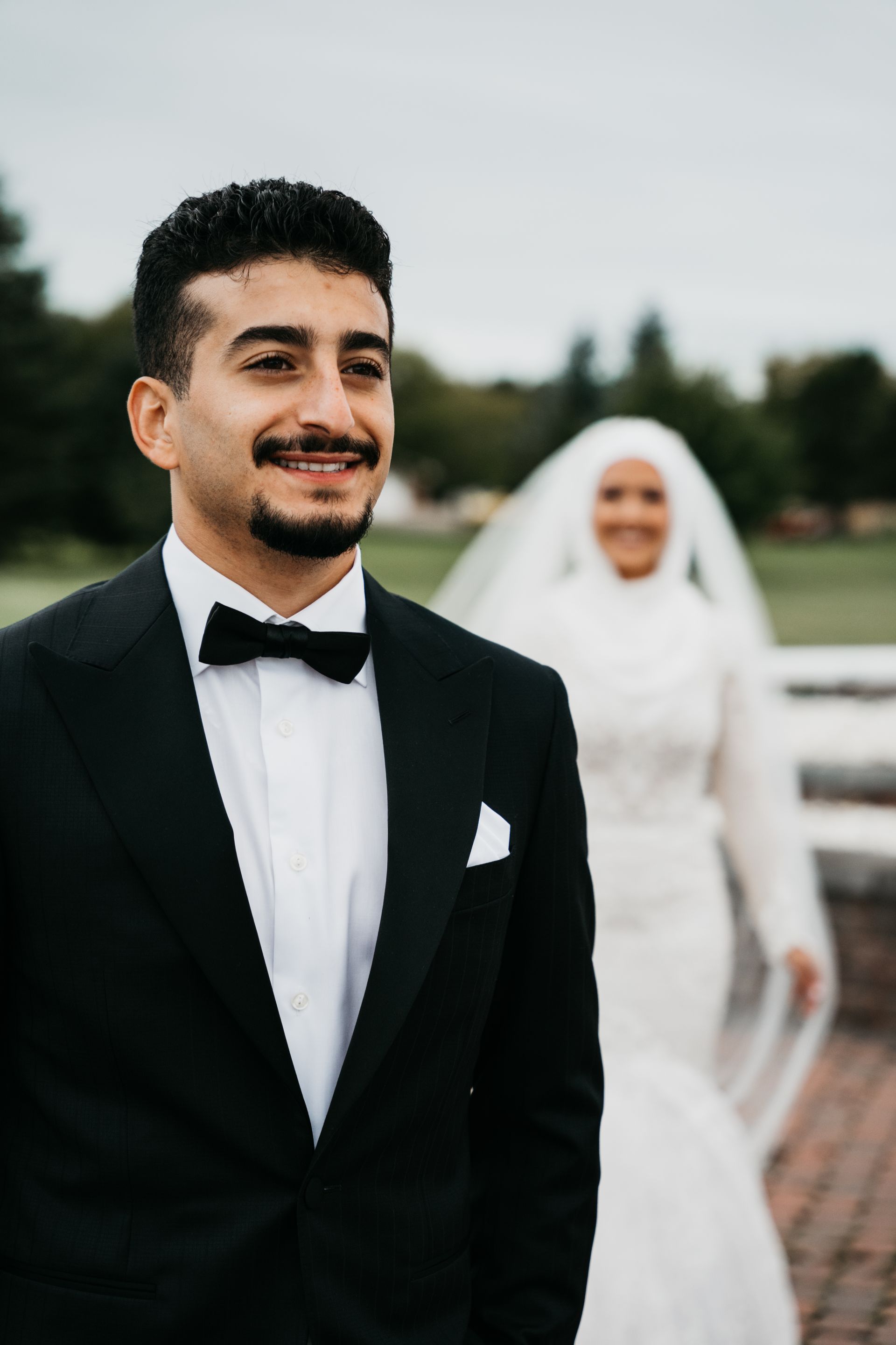 A man in a suit and bow tie is standing next to a woman in a white dress.
