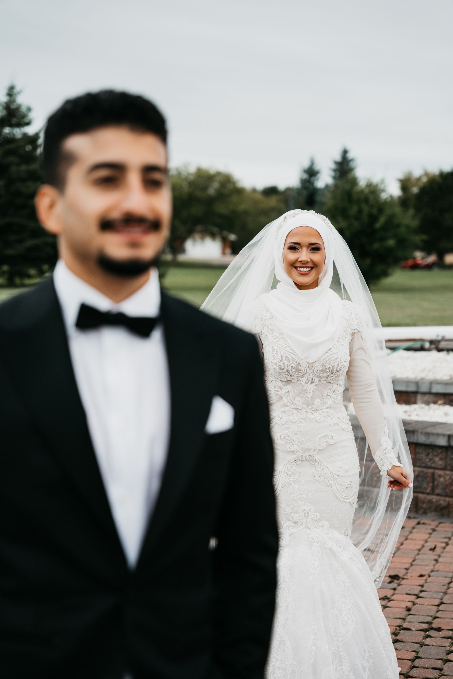 The bride is wearing a hijab and the groom is wearing a tuxedo.