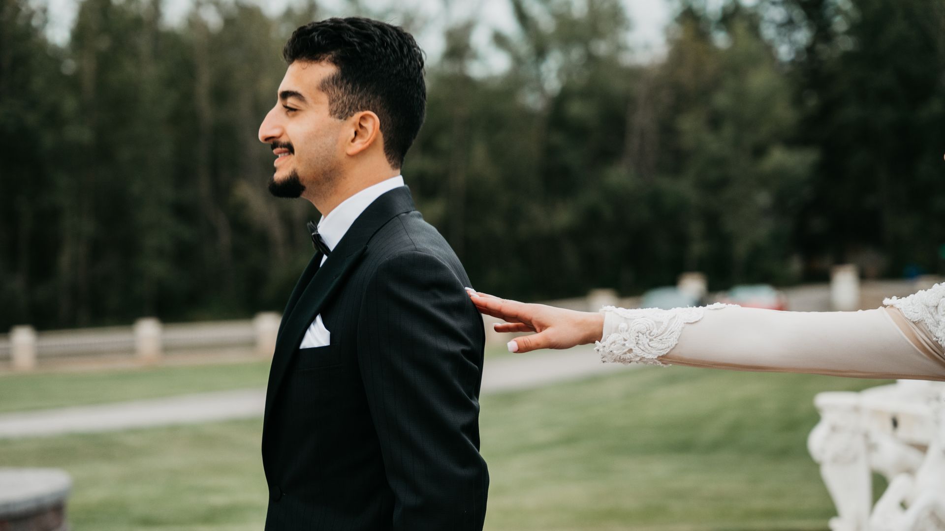 A bride is putting her hand on the back of a groom.