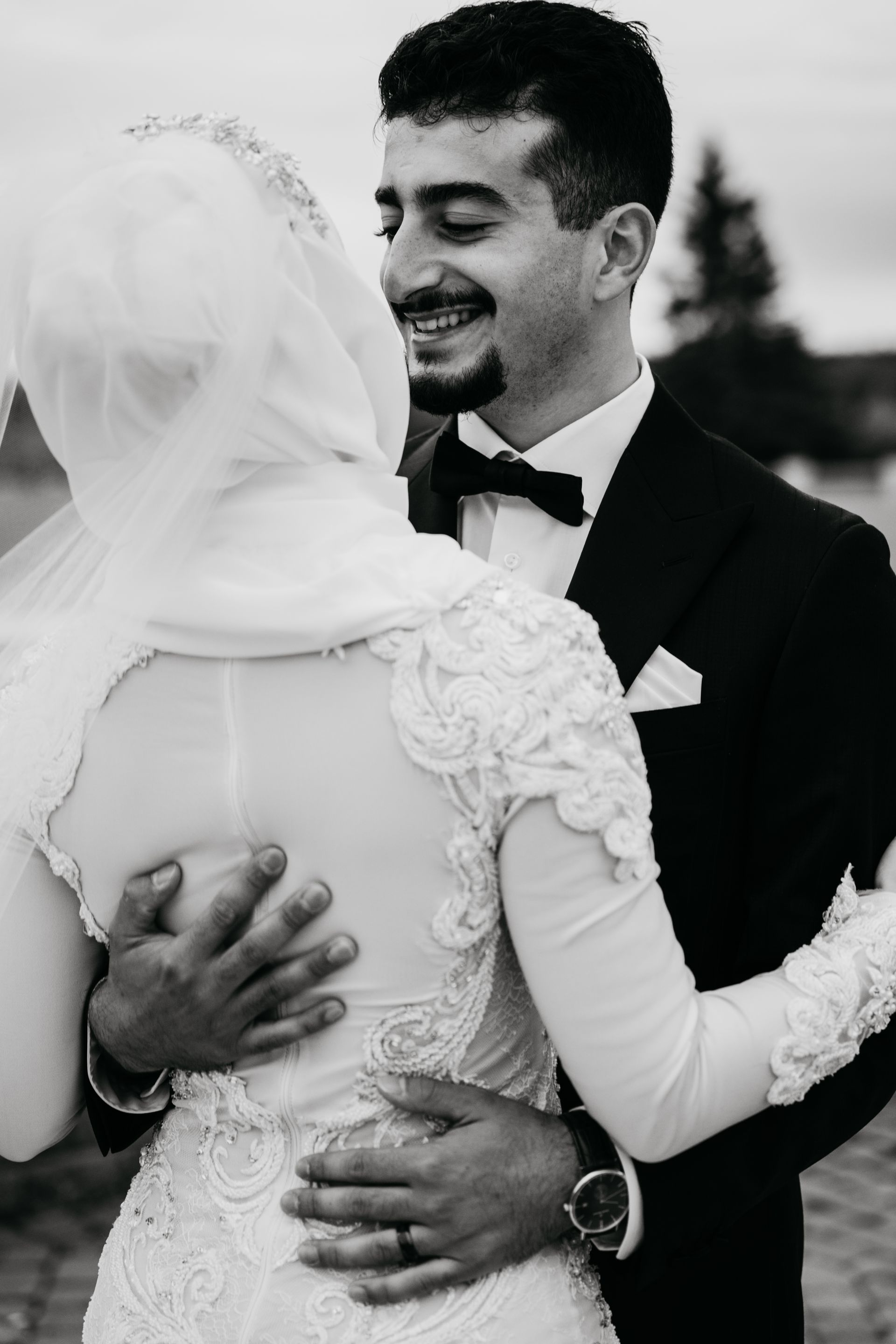 A black and white photo of a bride and groom hugging each other.