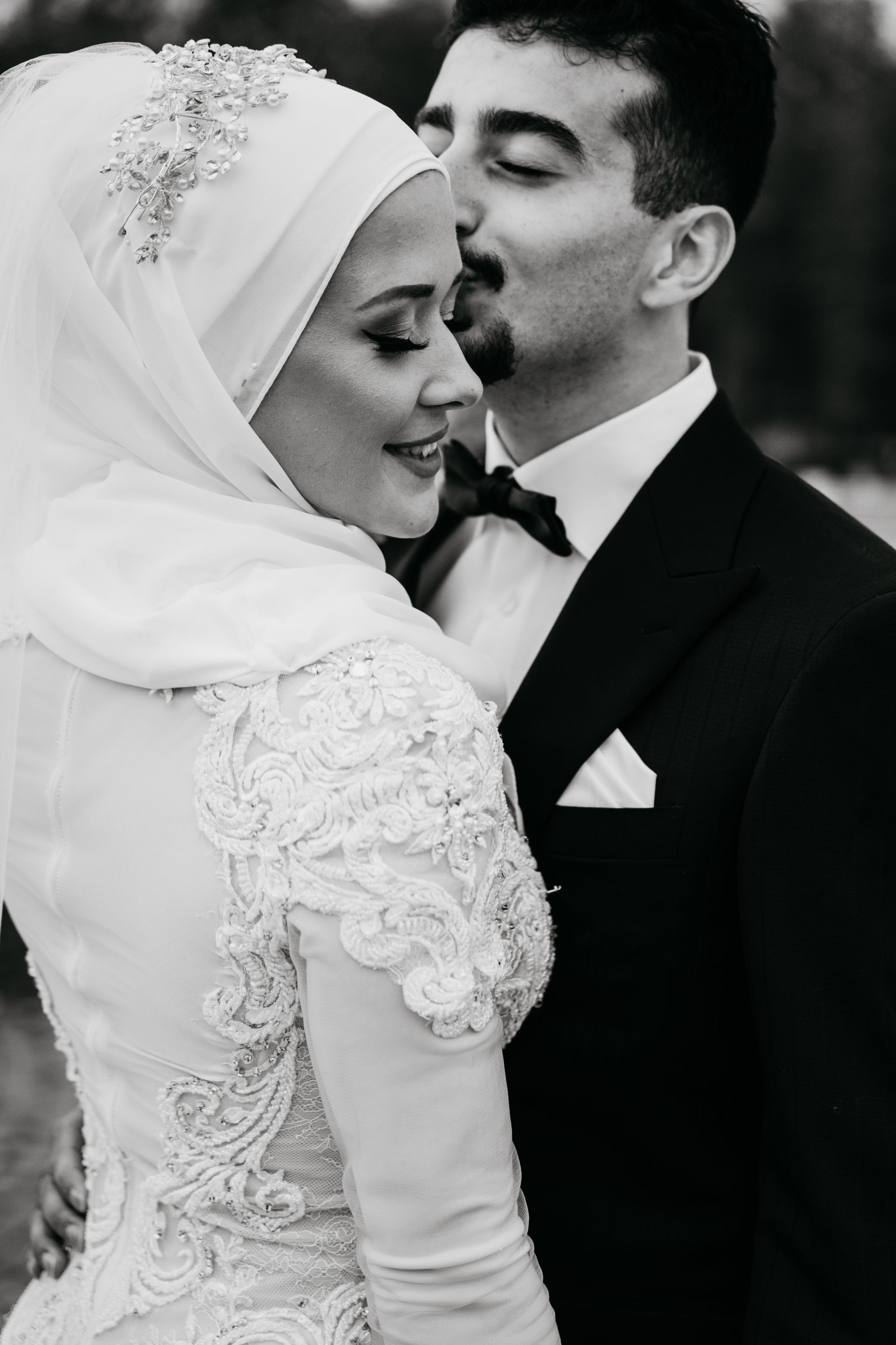 A bride and groom are kissing in a black and white photo.