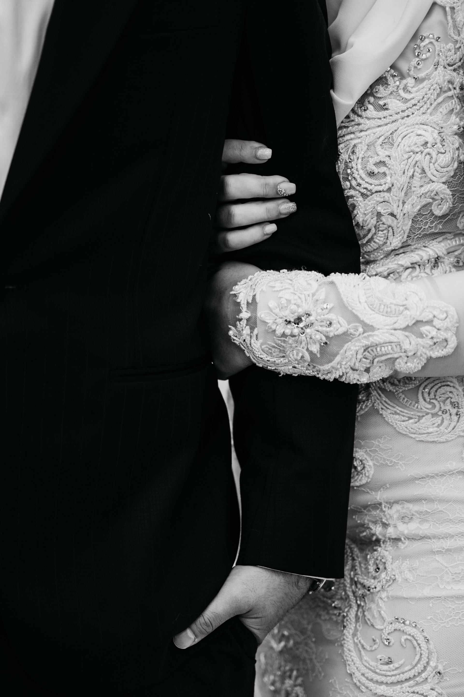 A black and white photo of a bride and groom holding hands.