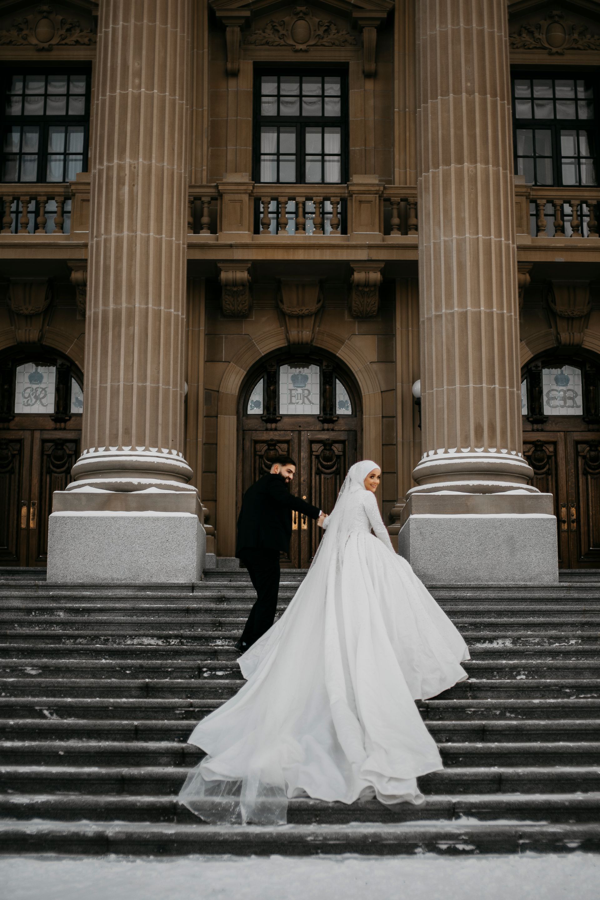 A bride and groom are walking down the stairs of a building.