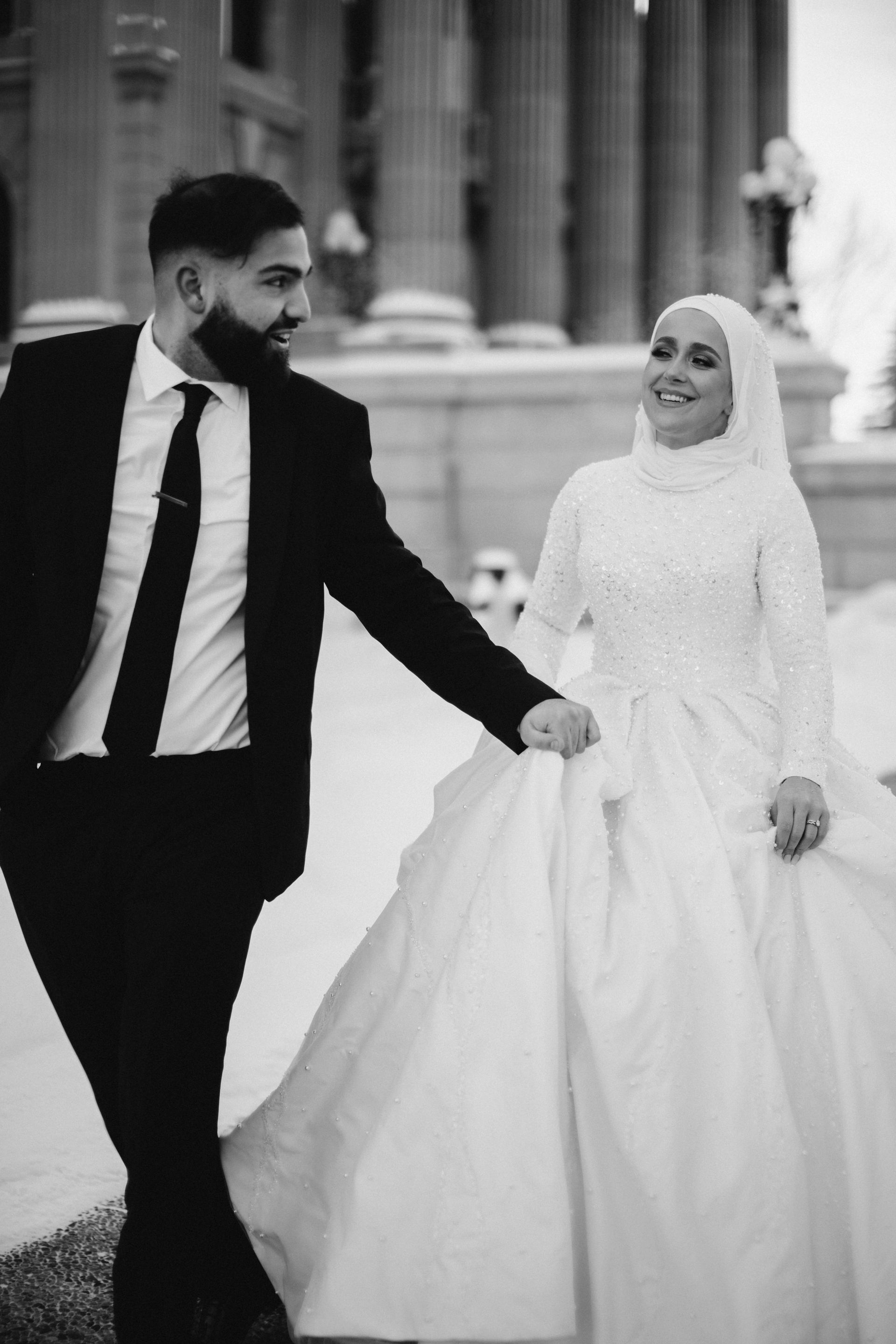 A black and white photo of a bride and groom holding hands.