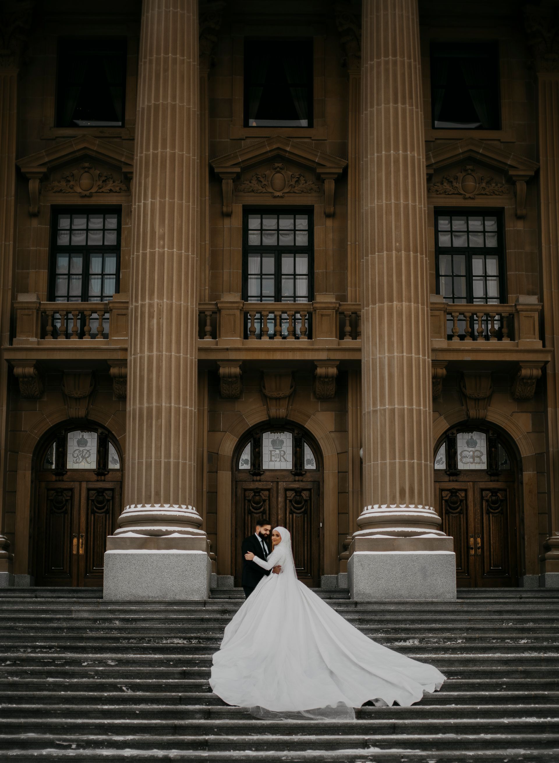 A bride and groom are kissing on the steps of a building.
