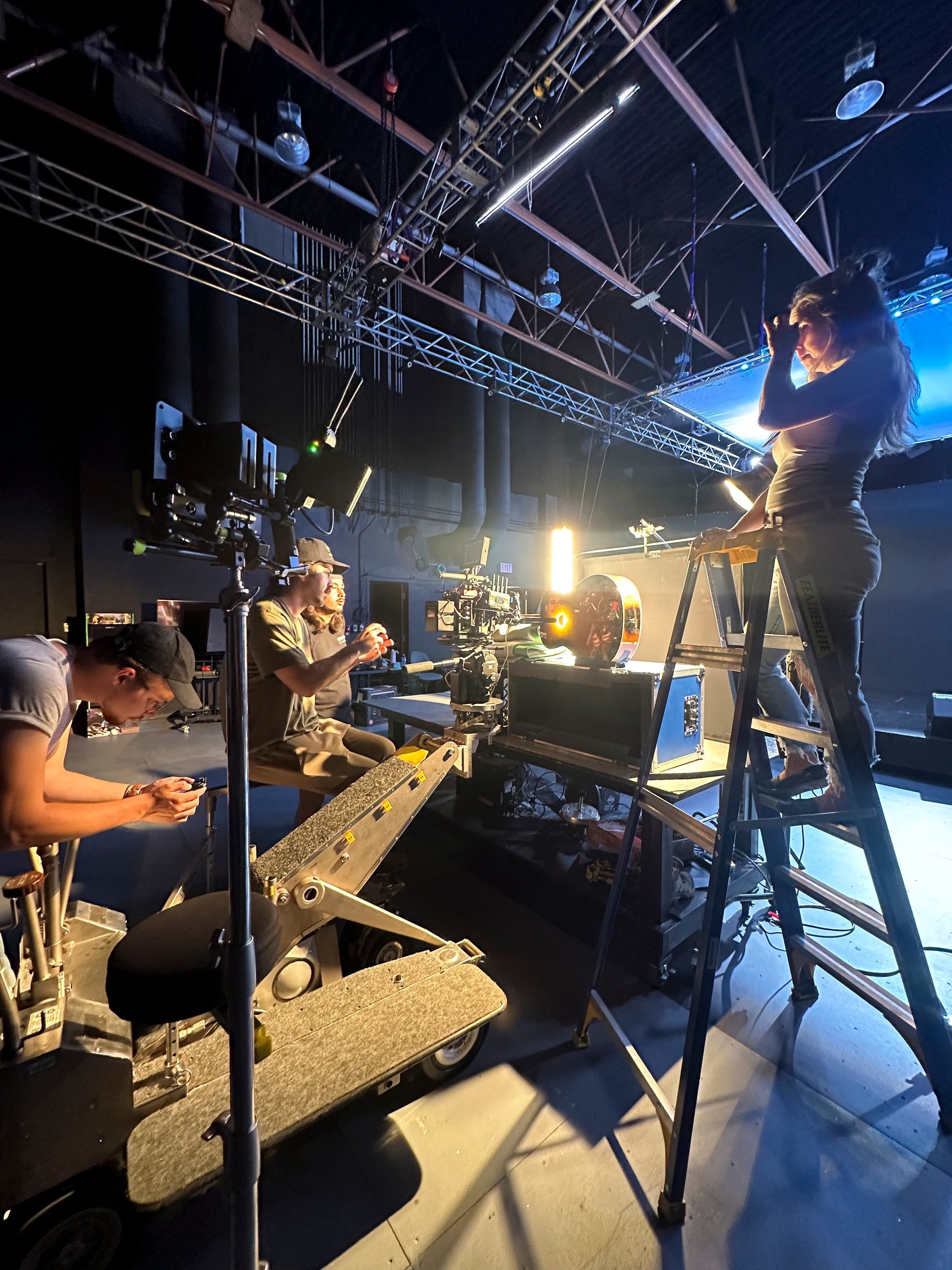 A group of people are working on a set in a dark room.