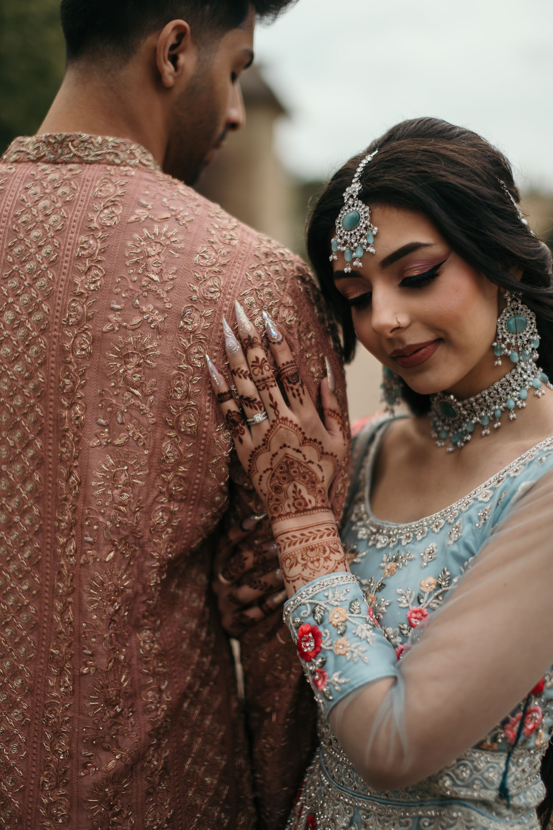 A man and a woman are standing next to each other and the woman is wearing a blue dress.