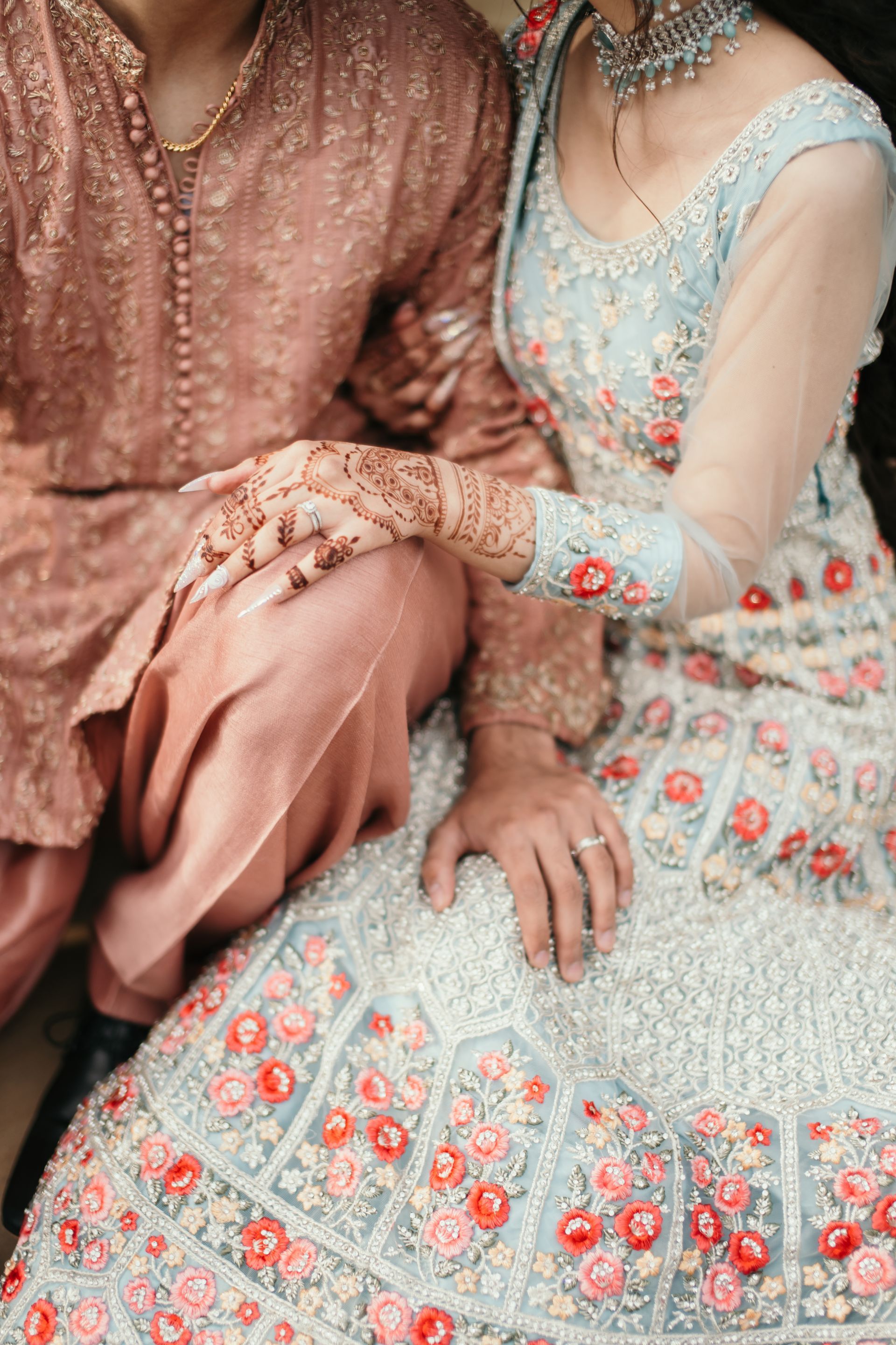 A bride and groom are sitting next to each other holding hands.