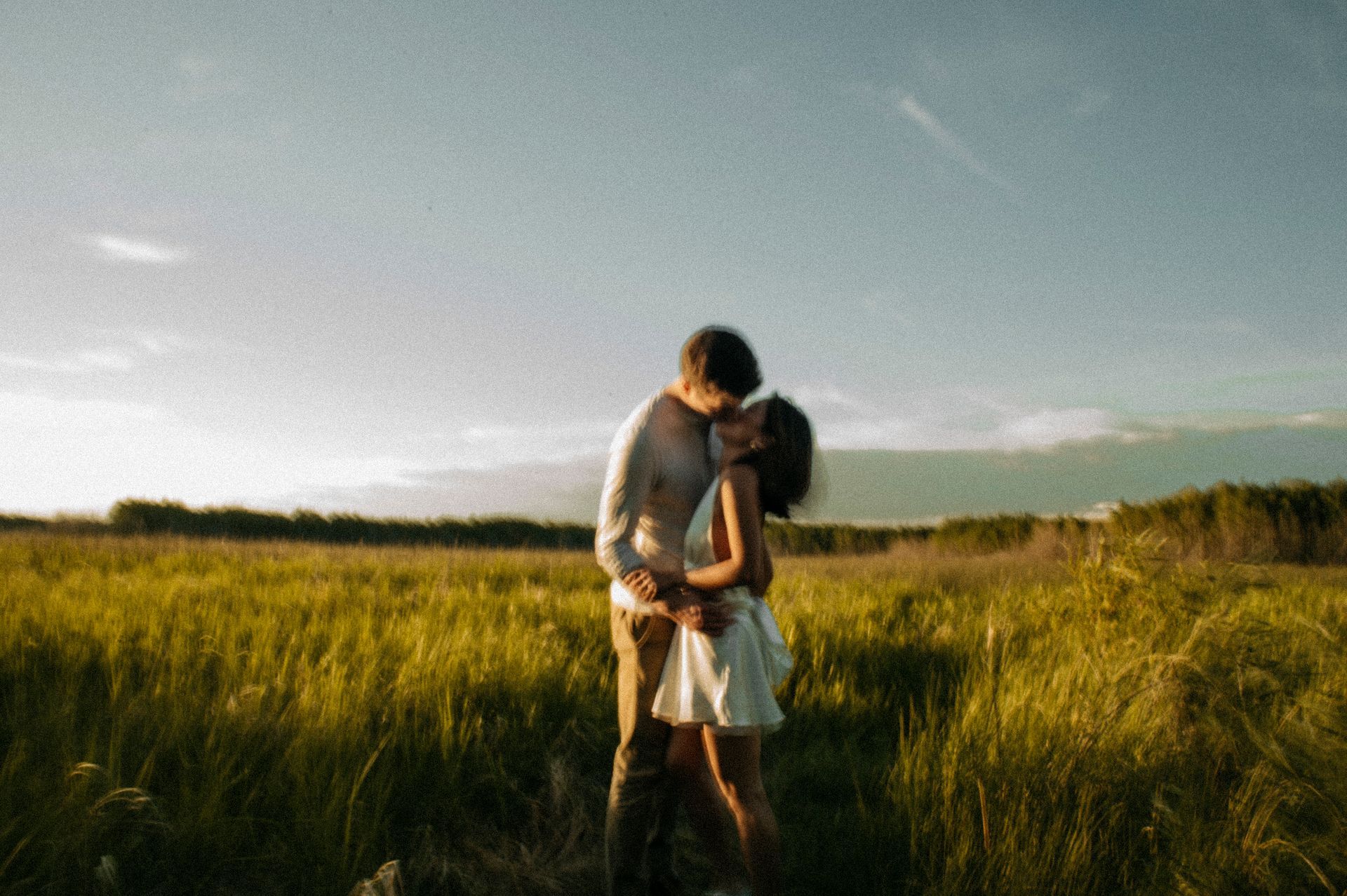 A man and a woman are kissing in a field.
