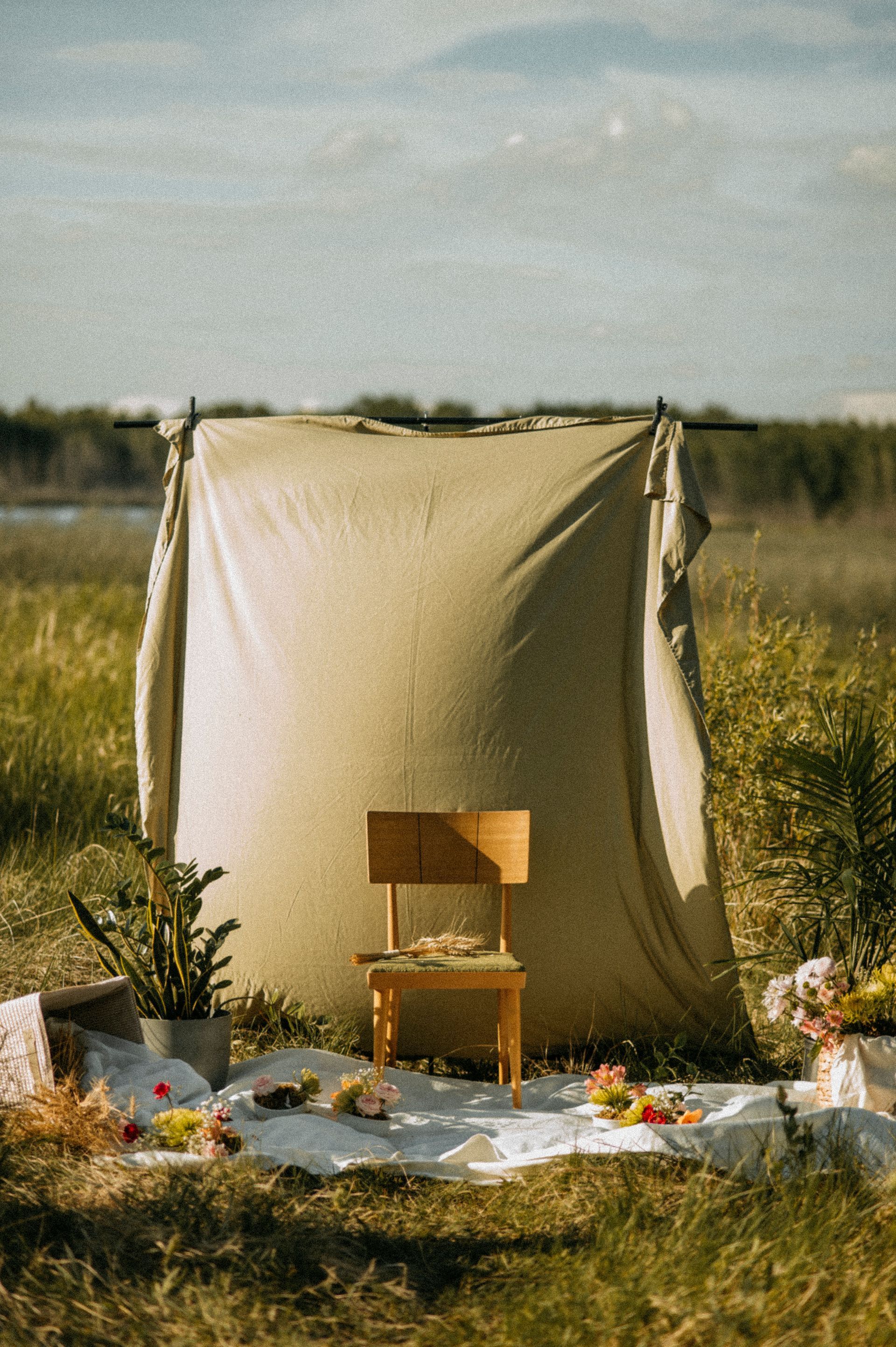 A chair is sitting in front of a tent in a field.