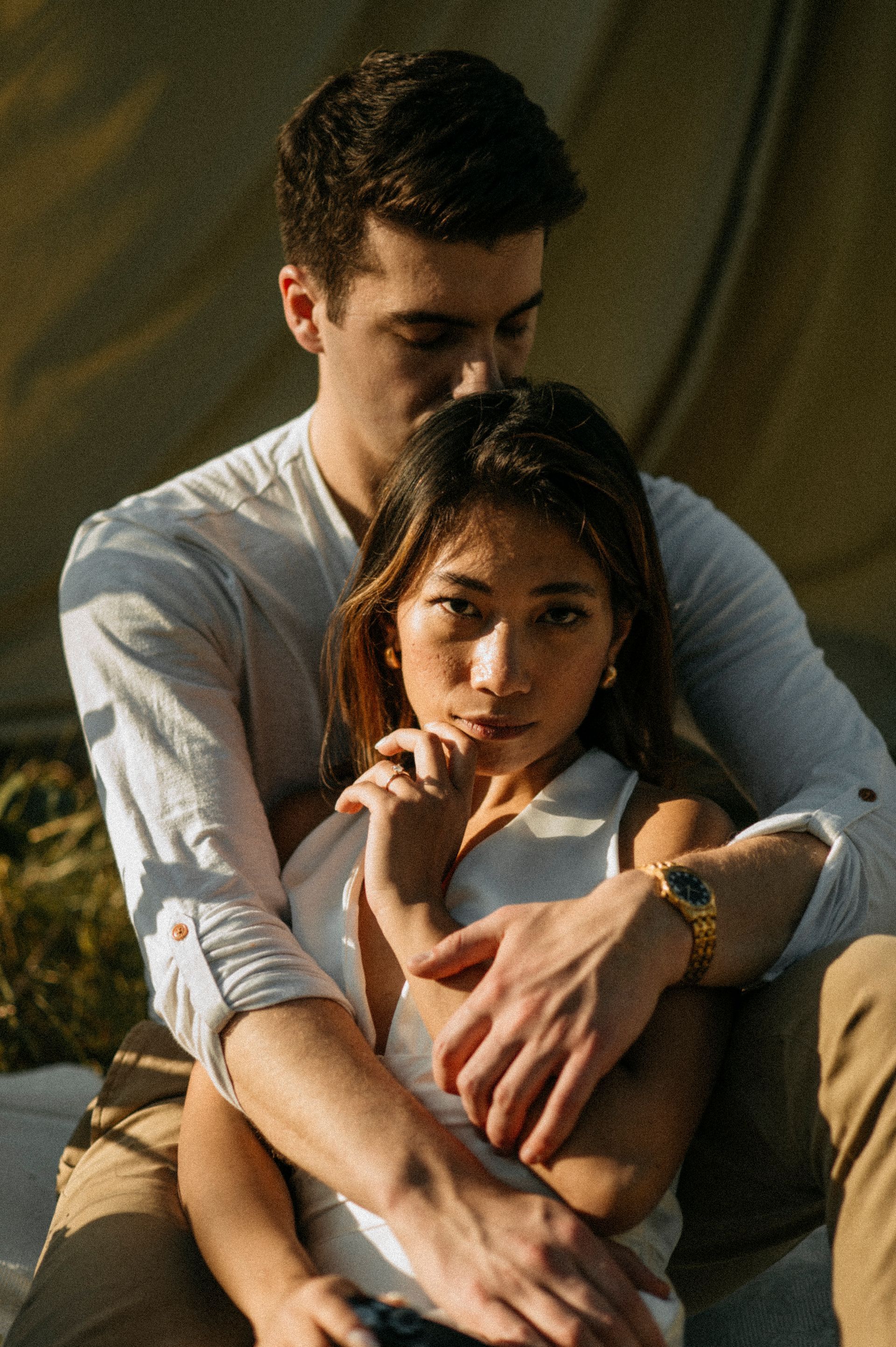 A man and a woman are hugging each other while sitting next to each other.