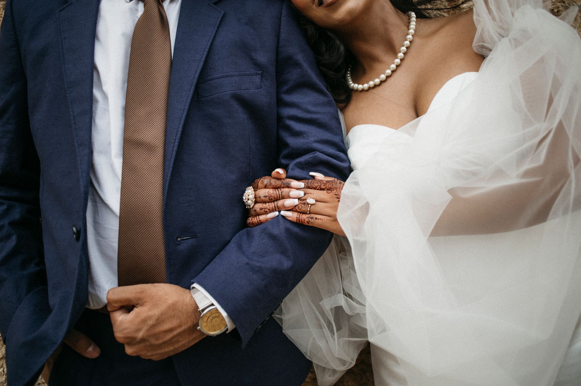 A man in a suit and tie is holding a woman in a wedding dress.