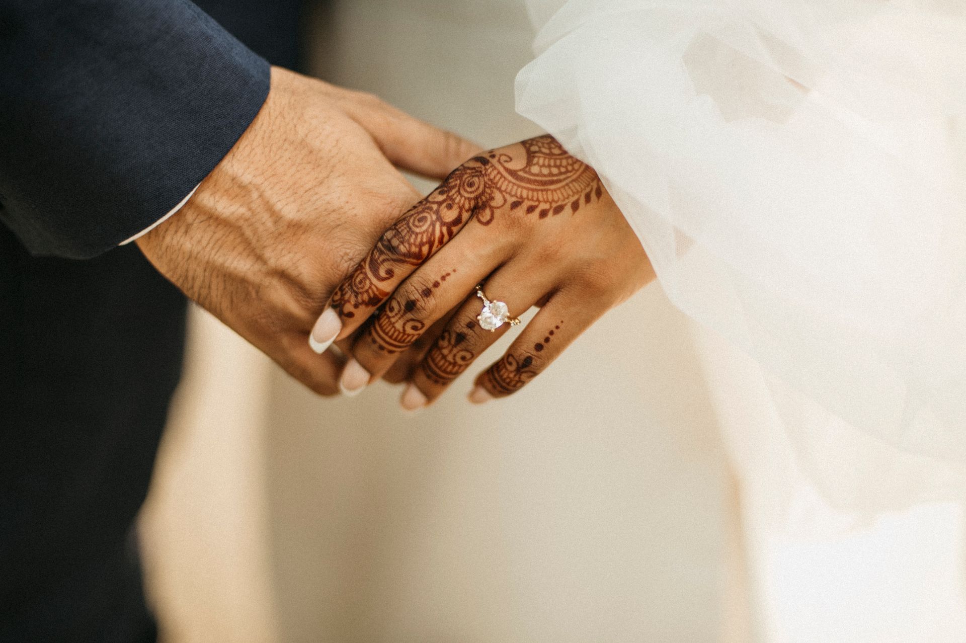 A bride and groom are holding hands with their wedding rings on their fingers.
