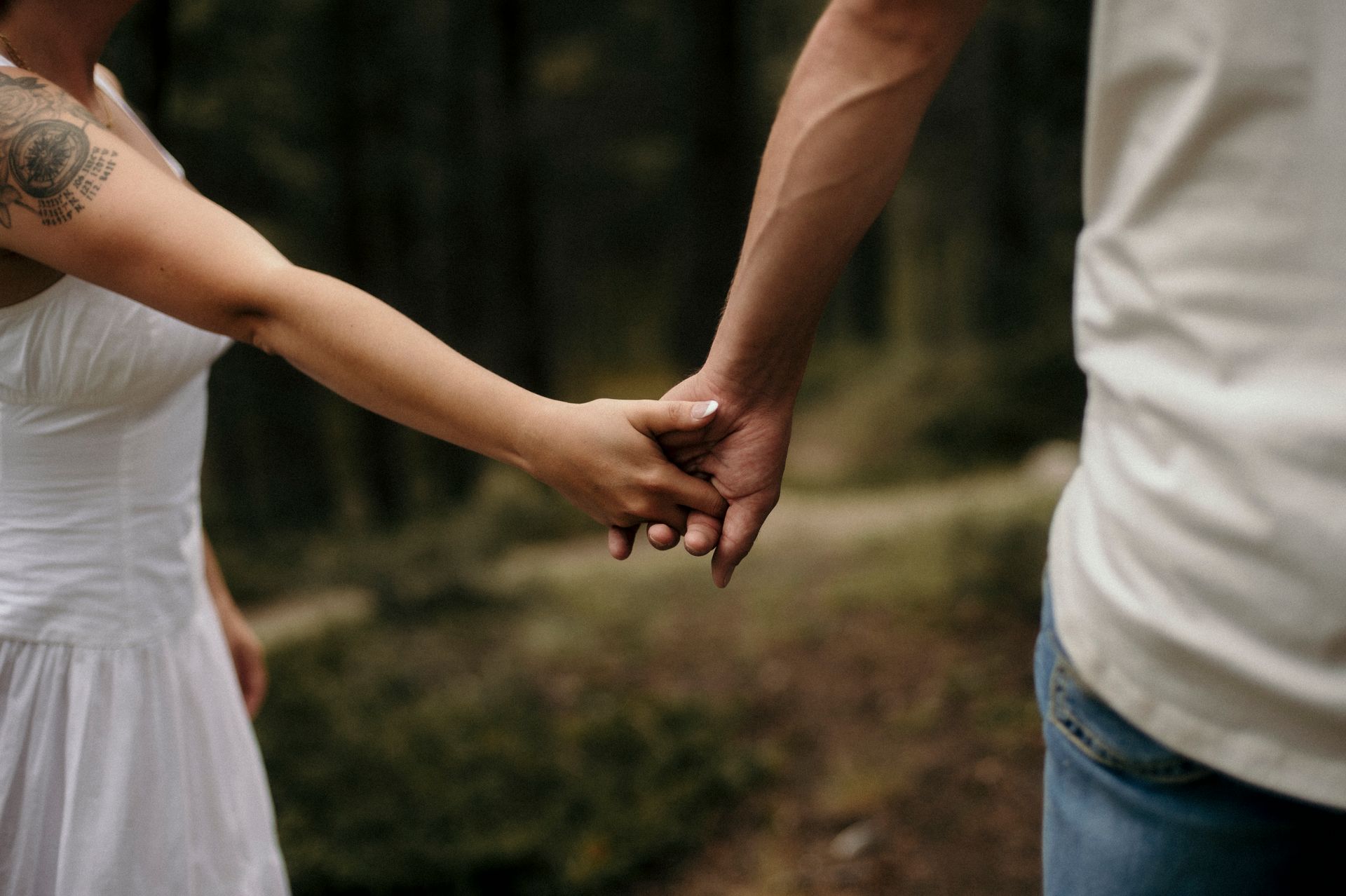 A man and a woman are holding hands in the woods.