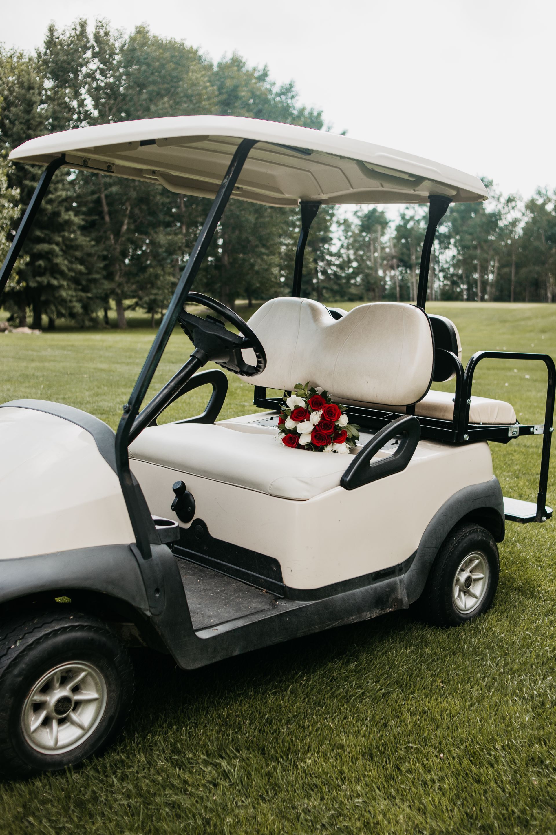 A white golf cart with a bouquet of flowers in the back seat.