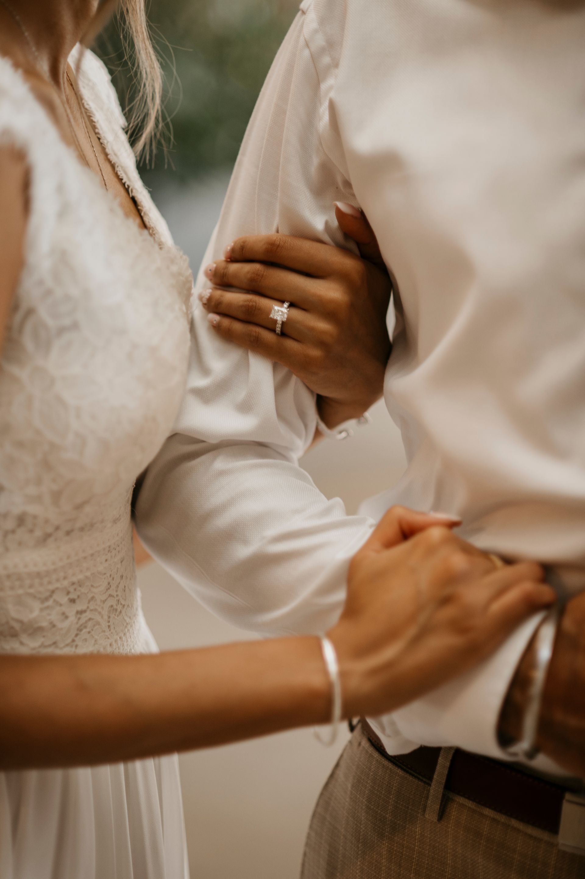 A bride and groom are holding hands and the bride is wearing a wedding ring.