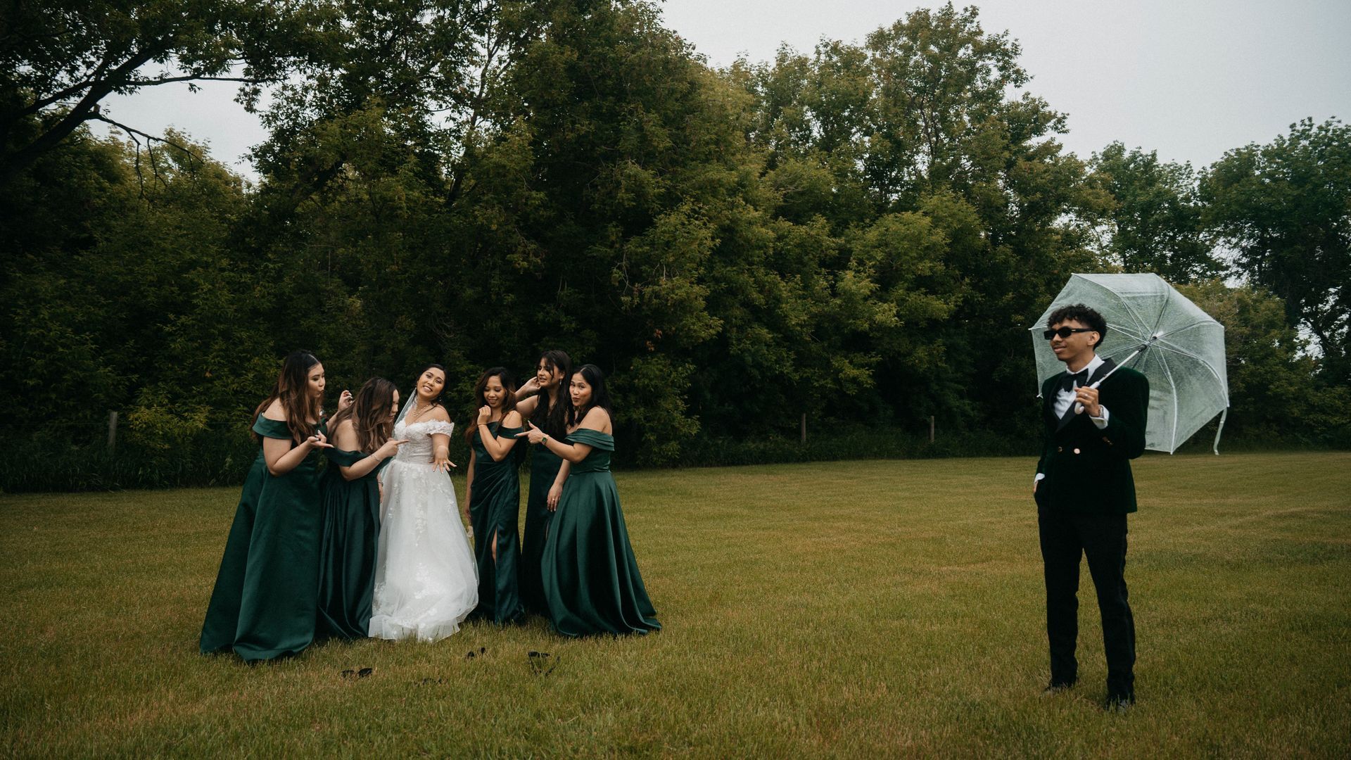 A bride and groom are posing for a picture with their bridesmaids in a field.