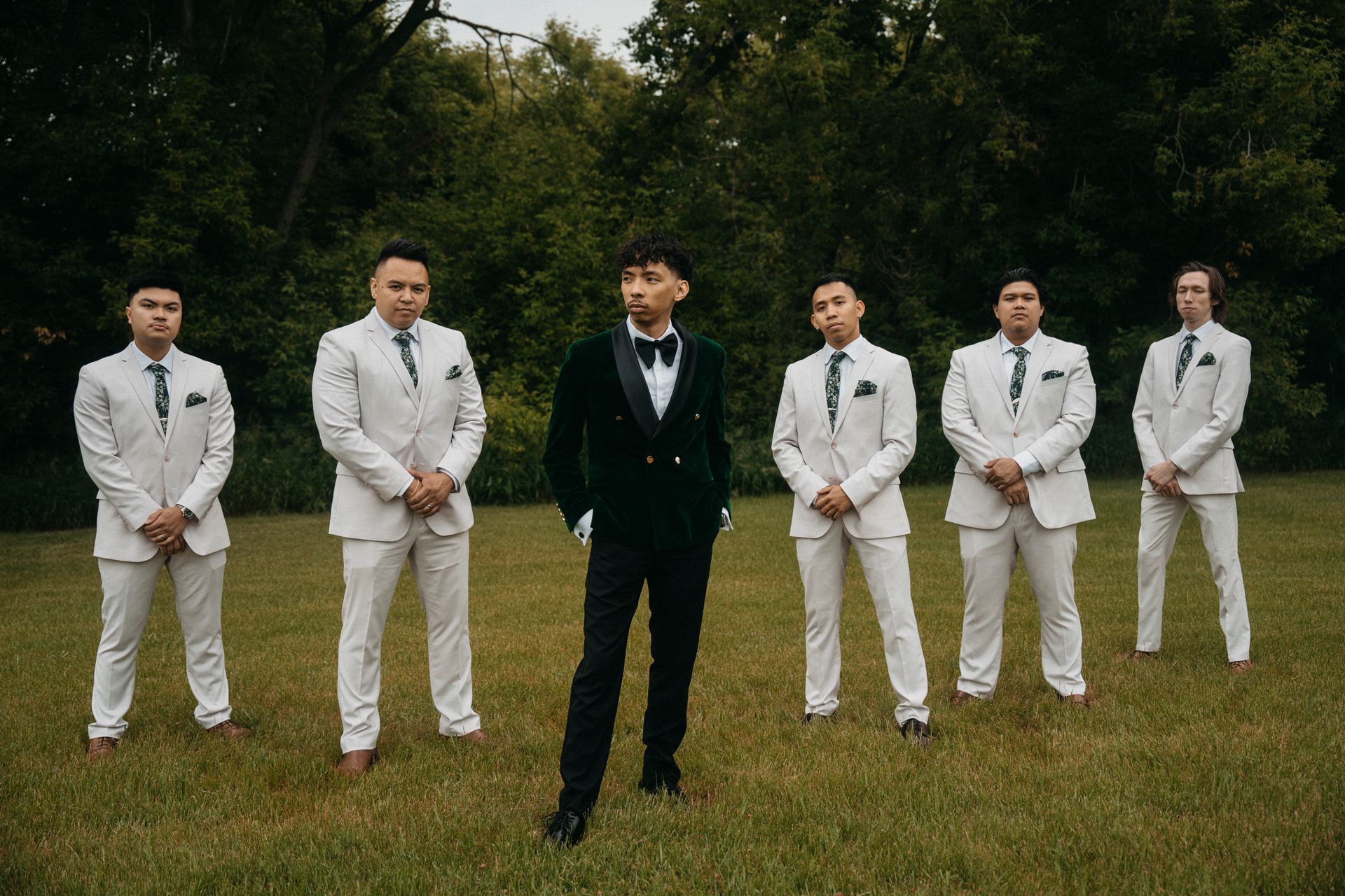 A groom and his groomsmen are posing for a picture in a field.