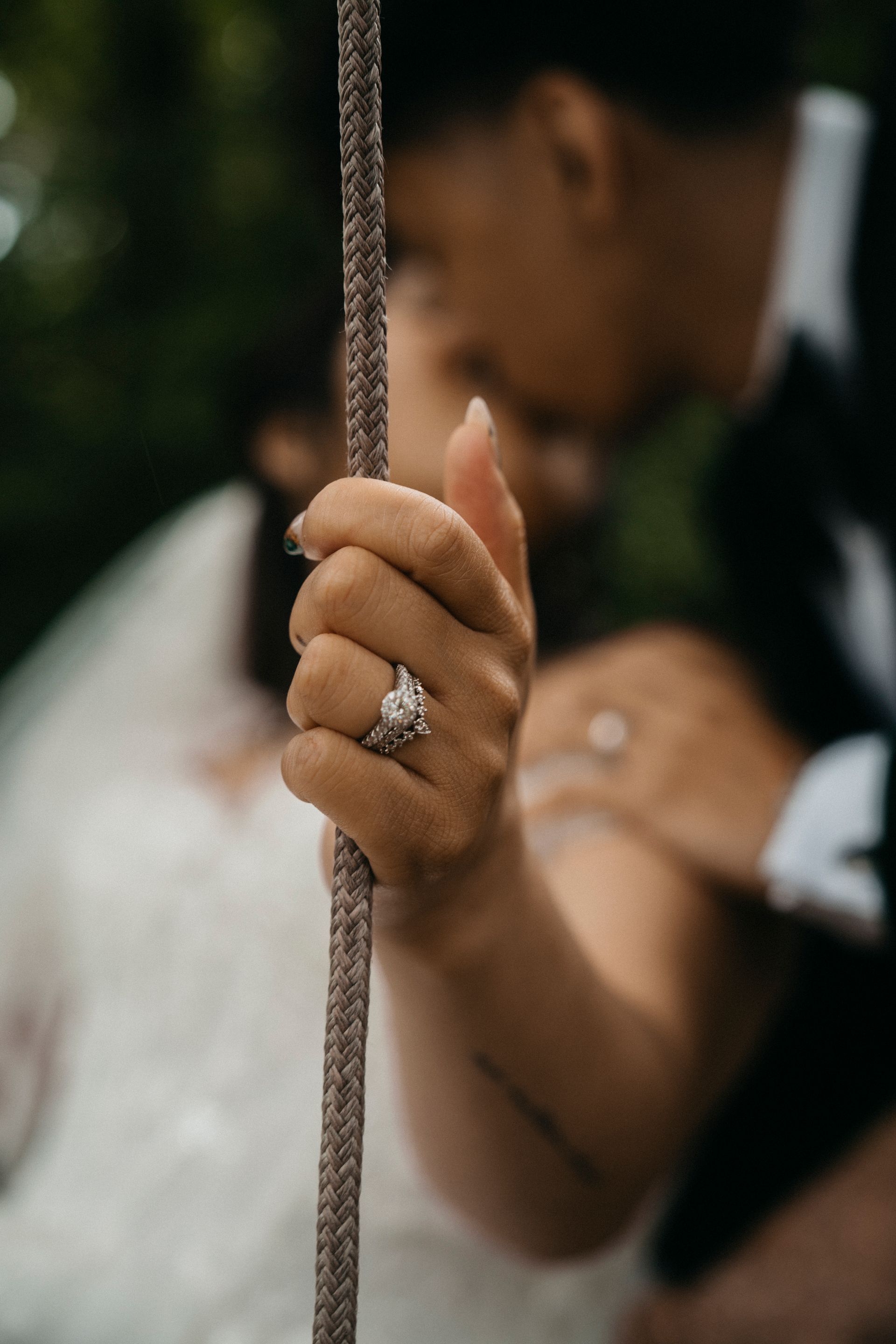 A close up of a person holding a rope with a ring on their finger.