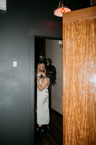 A bride and groom are hugging each other in a hallway.