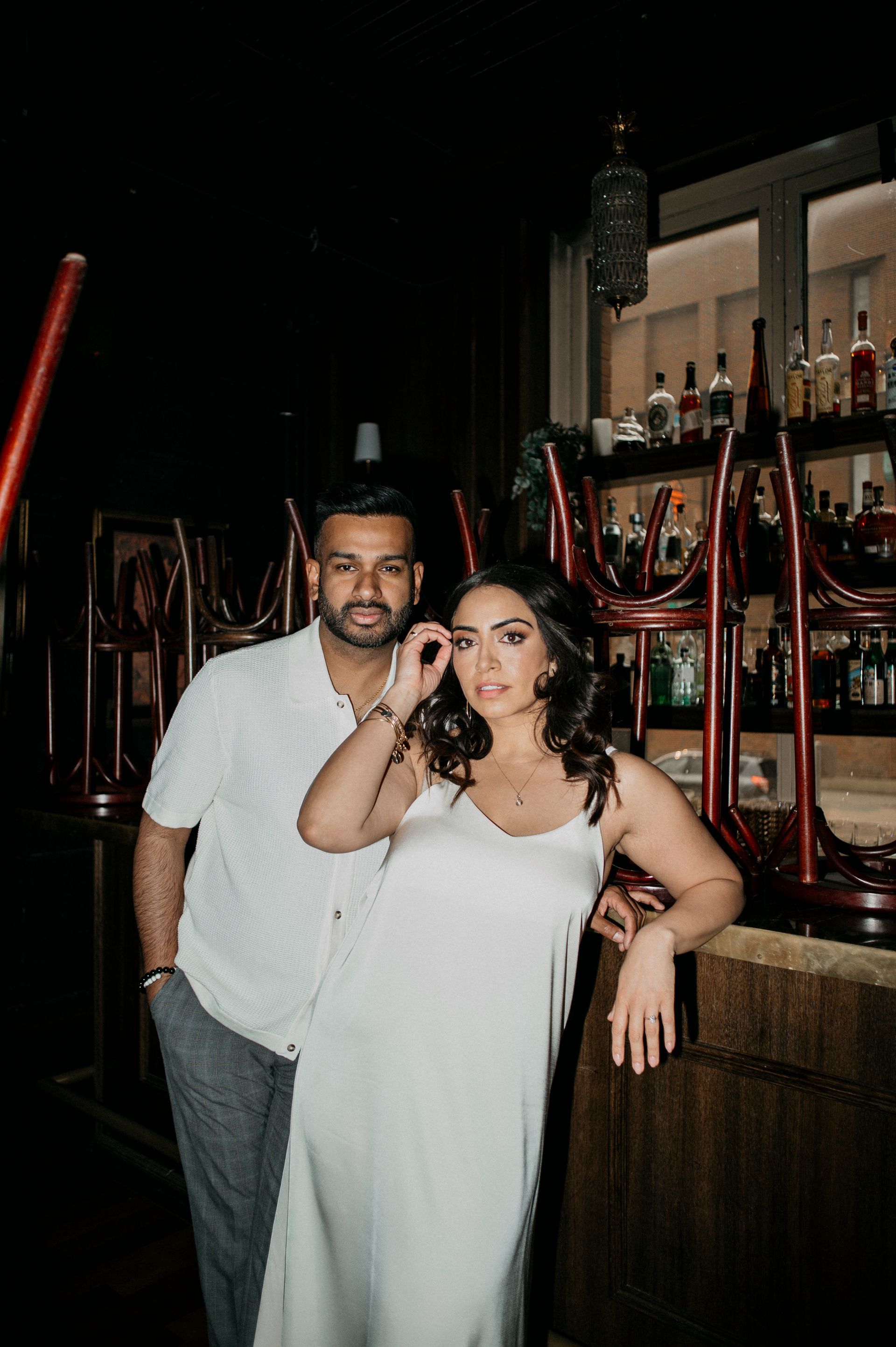 A man and a woman are standing next to each other in front of a bar.