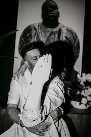 A black and white photo of a man kissing a woman on the cheek.