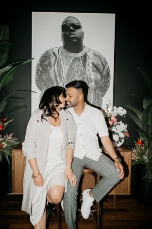 A man and a woman are kissing in front of a painting of a man.