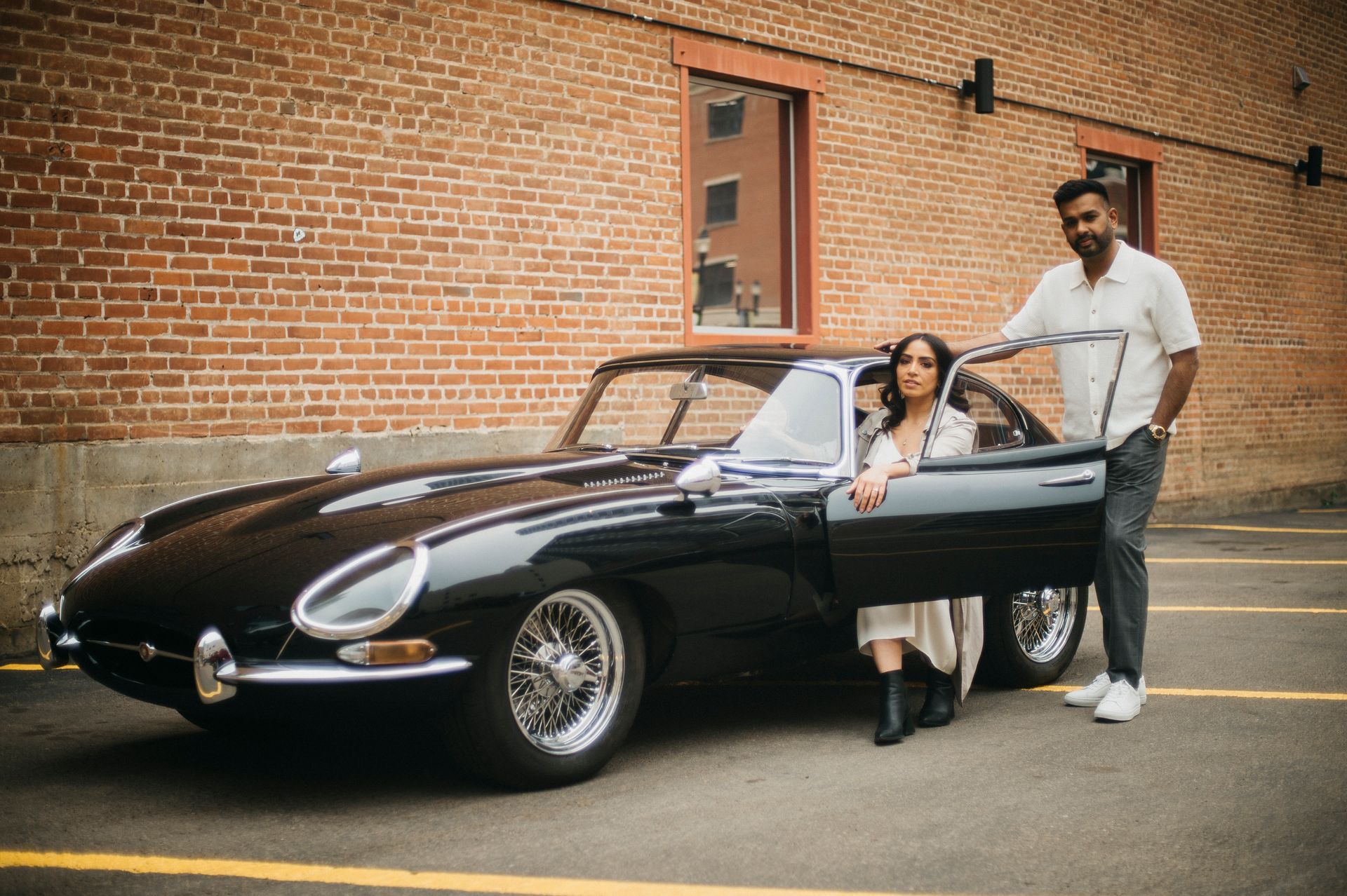 A man and a woman are standing next to a black car.