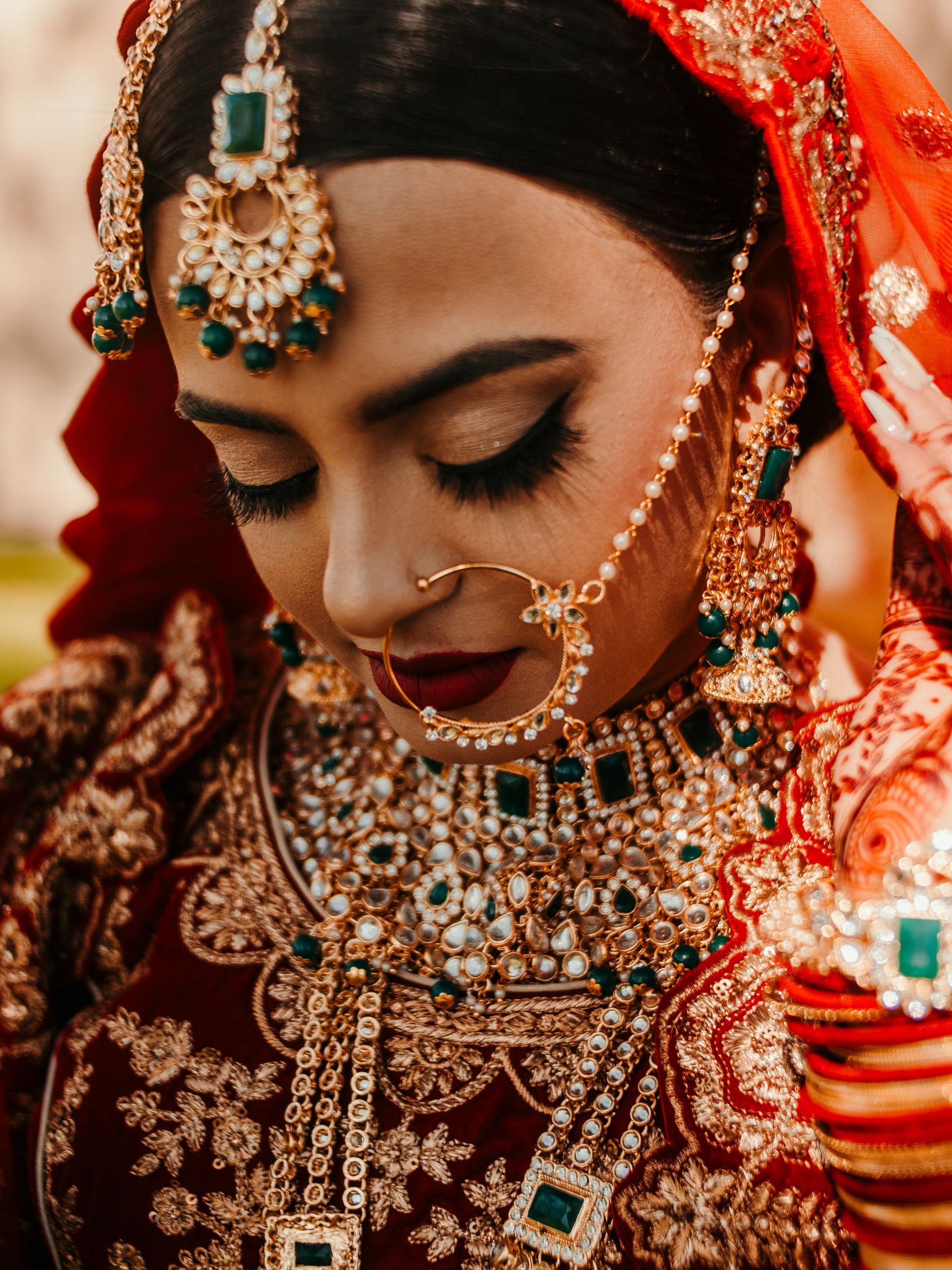 The bride is wearing a red and gold dress and jewelry.
