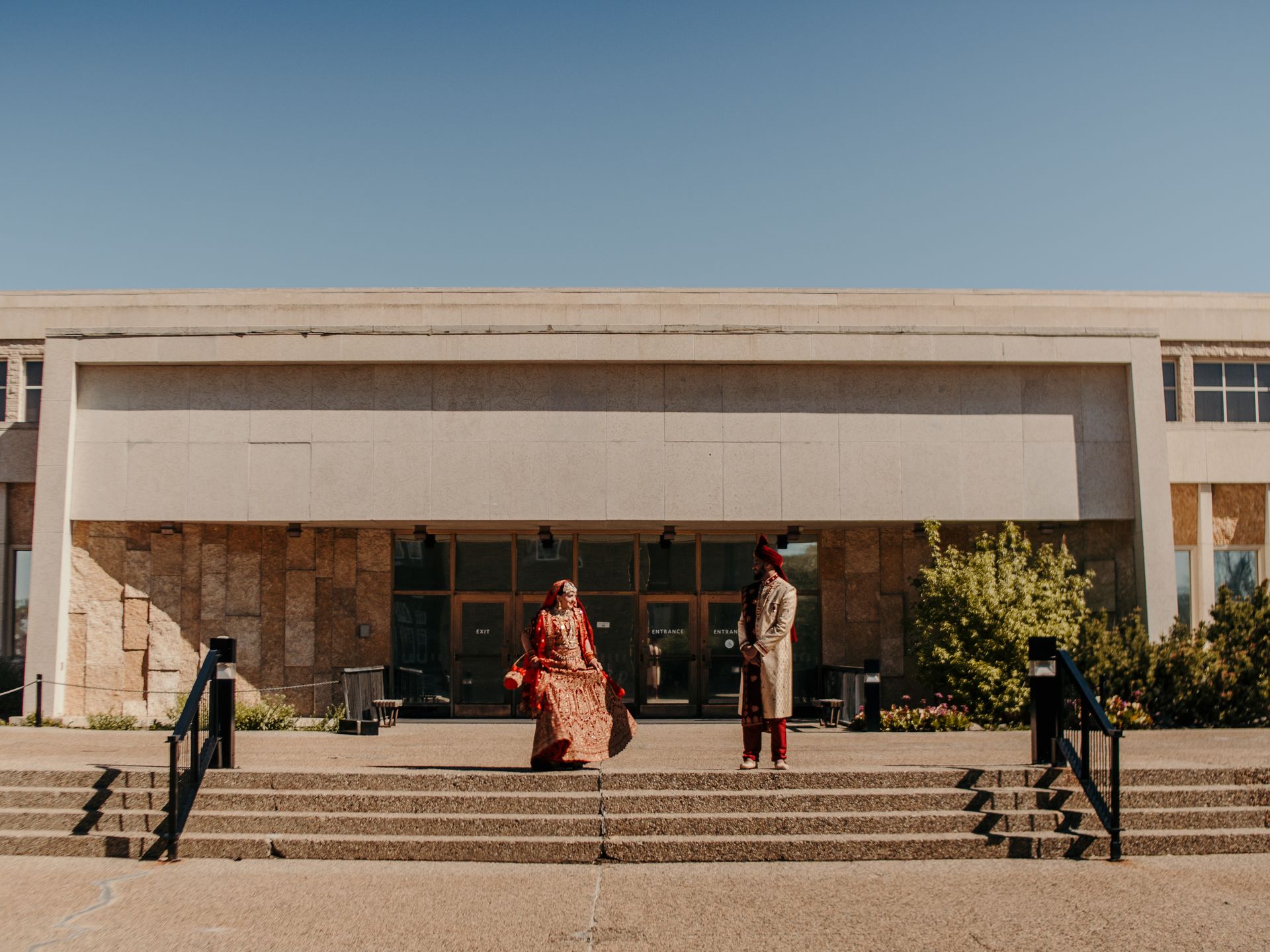 A bride and groom are standing on the steps of a building.